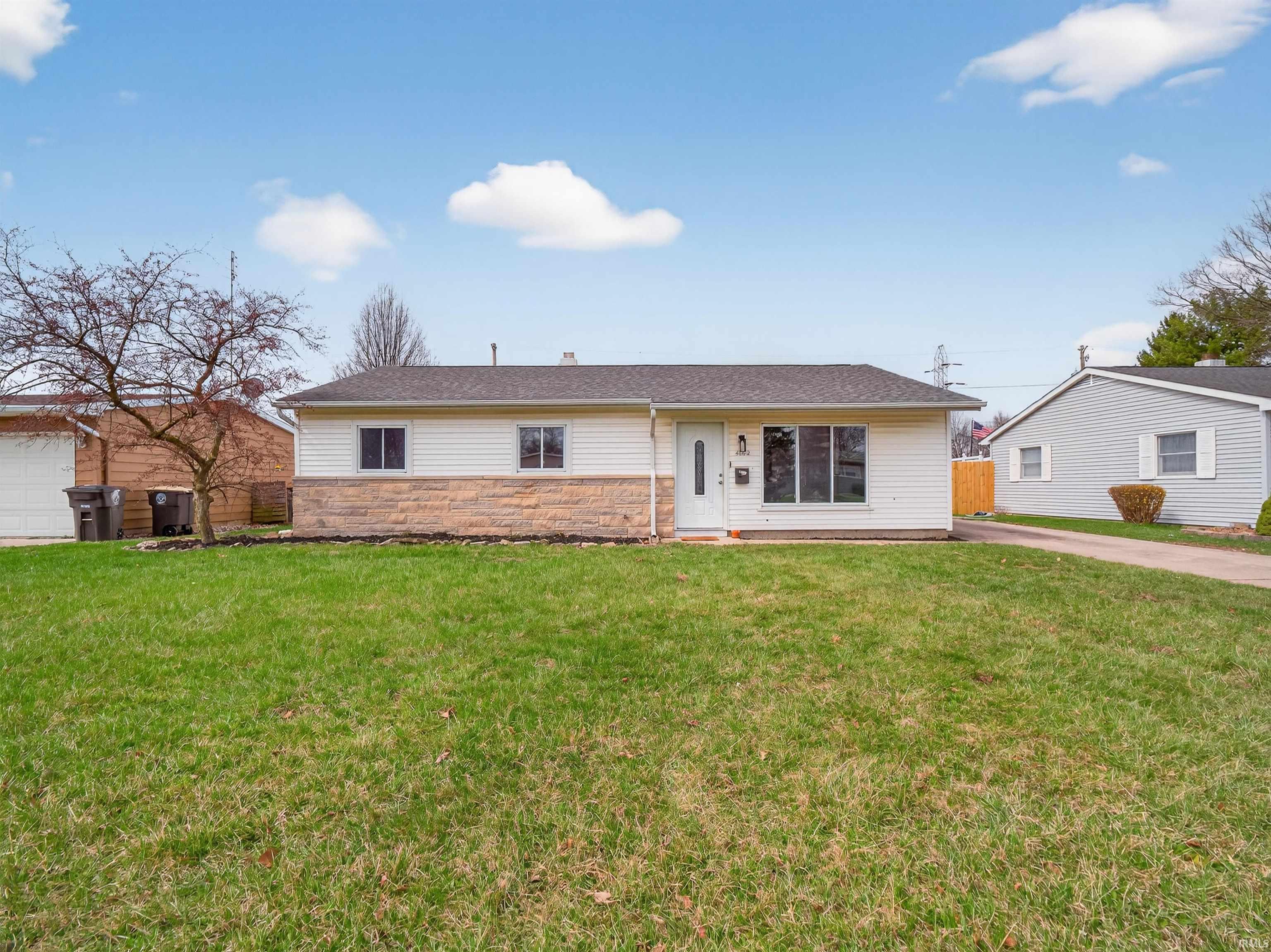Ranch-style home featuring stone siding and a shingled roof