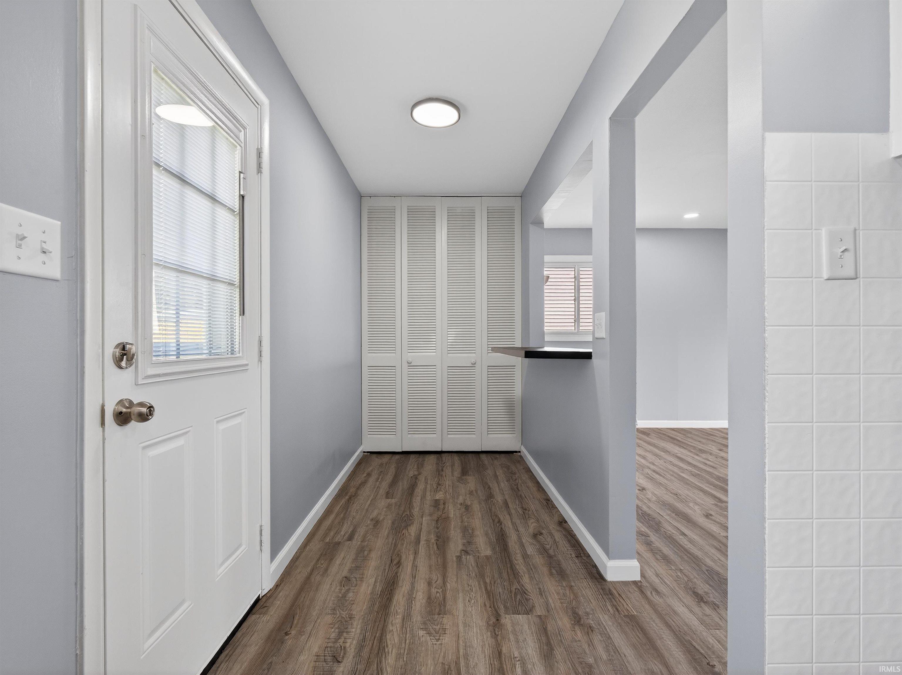 Hallway with dark wood-style flooring and baseboards