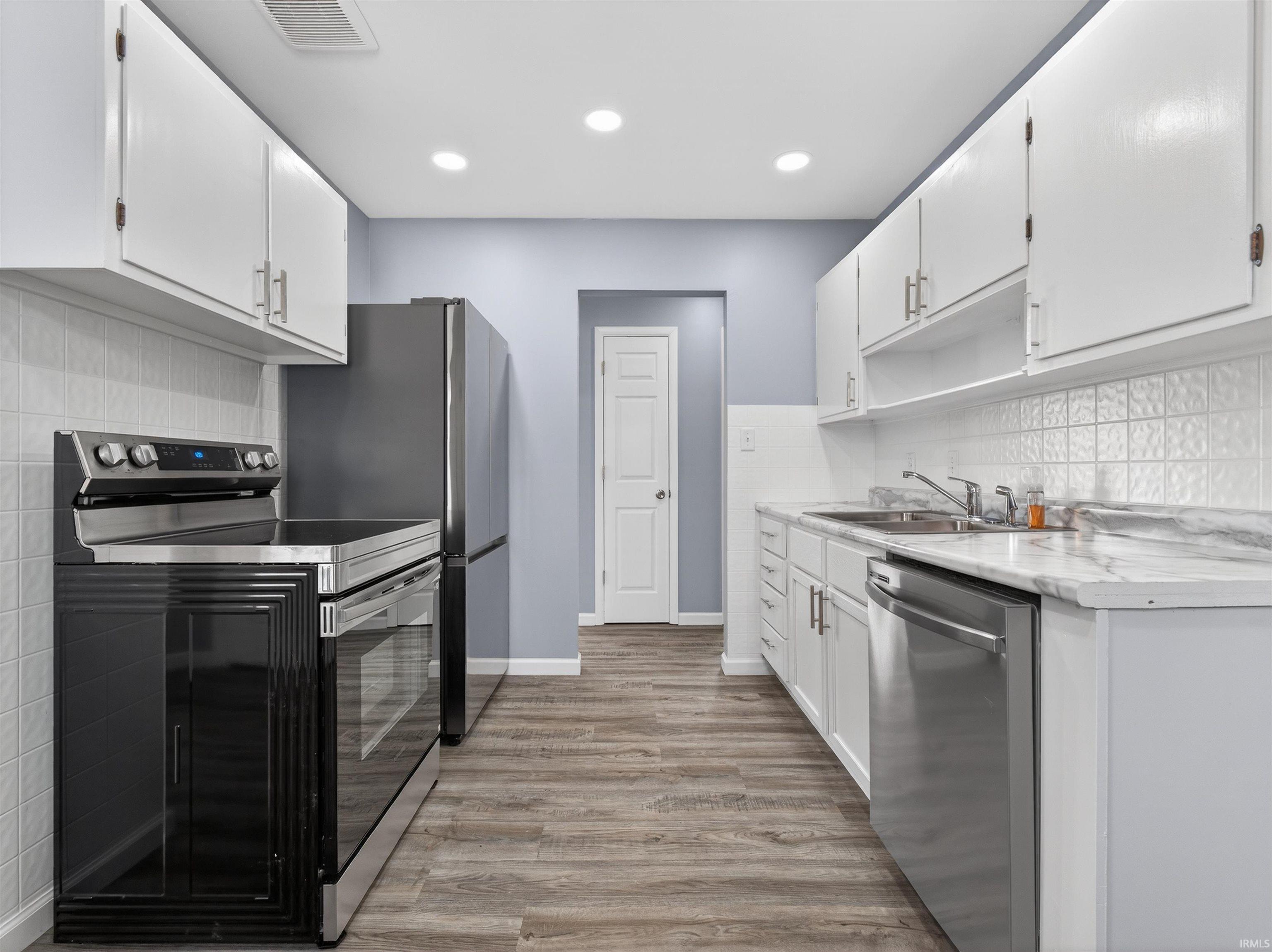 Kitchen with stainless steel appliances, white cabinets, light countertops, and recessed lighting
