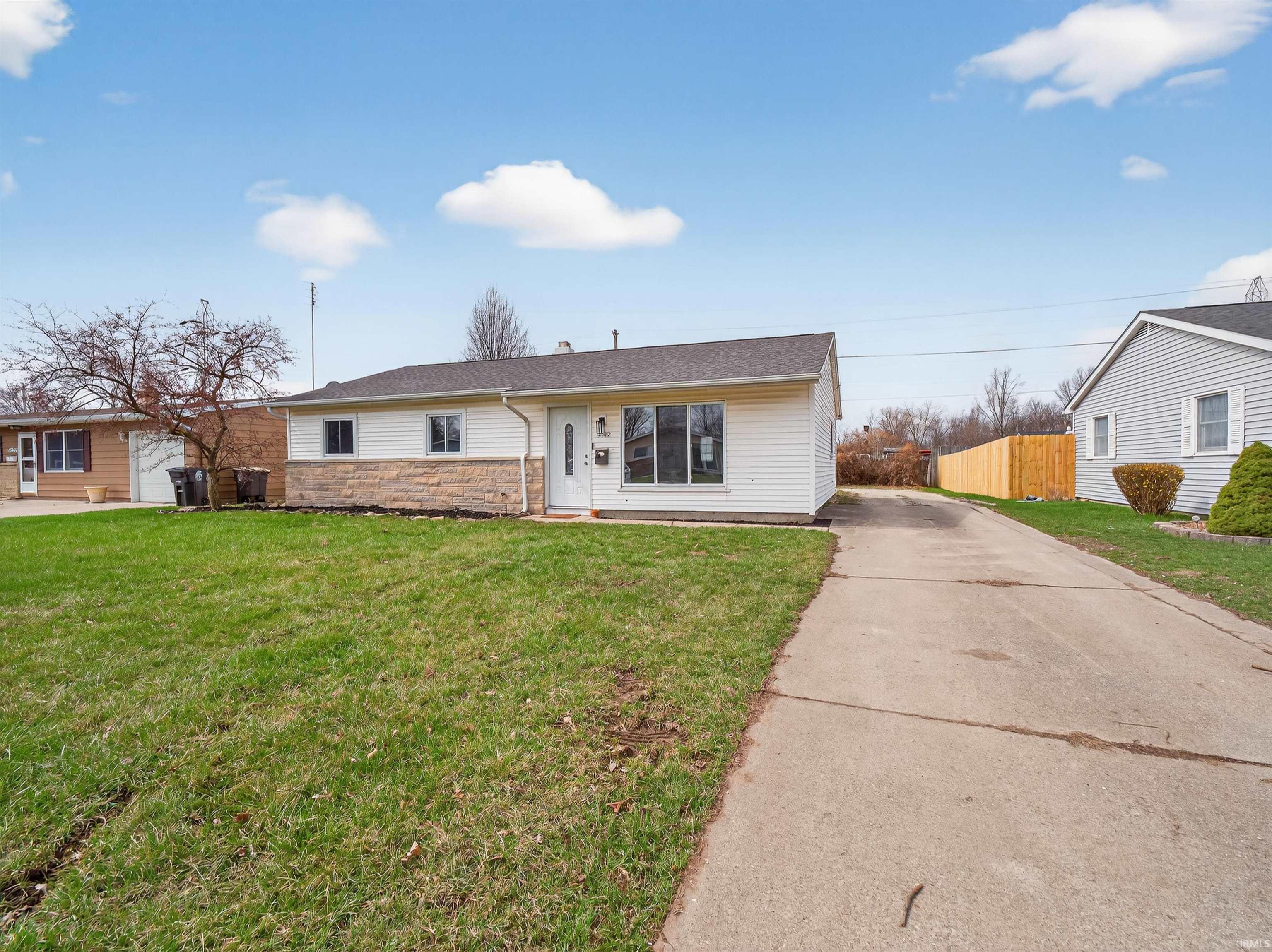 Single story home featuring stone siding, concrete driveway, and roof with shingles