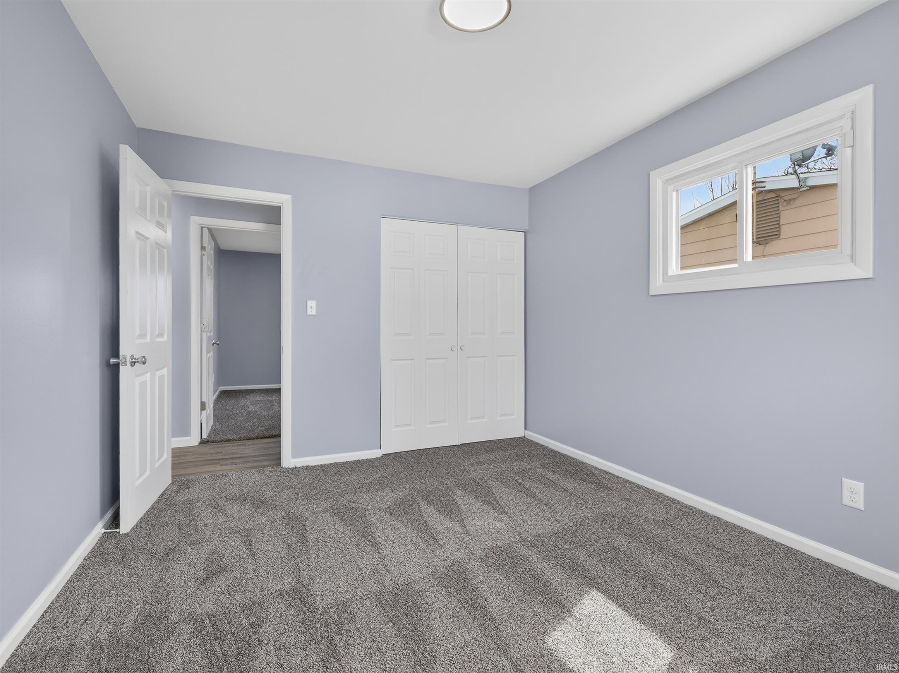Unfurnished bedroom featuring dark carpet and a closet