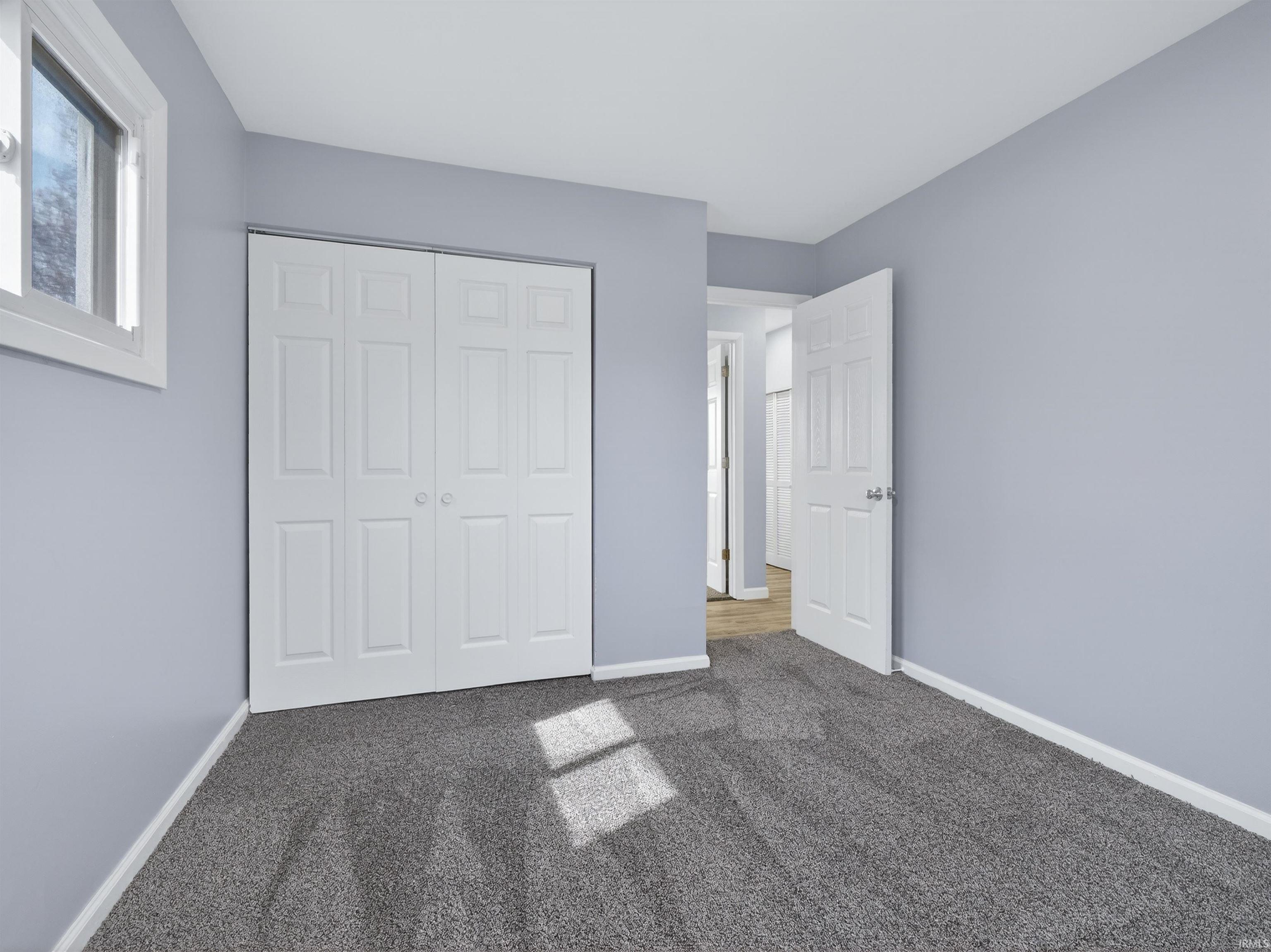 Unfurnished bedroom featuring dark carpet and a closet