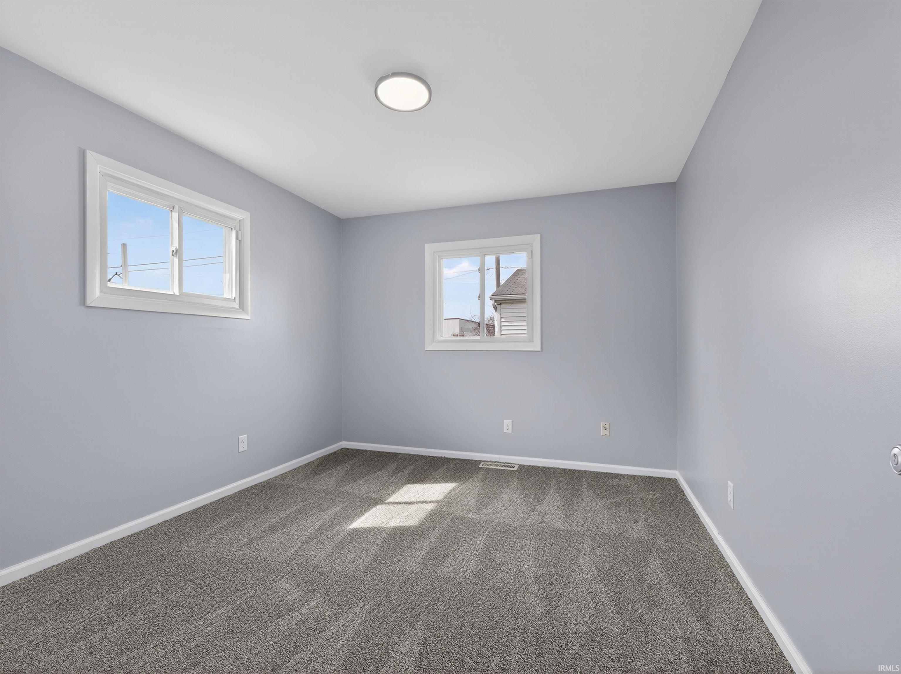 Empty room with baseboards and dark colored carpet