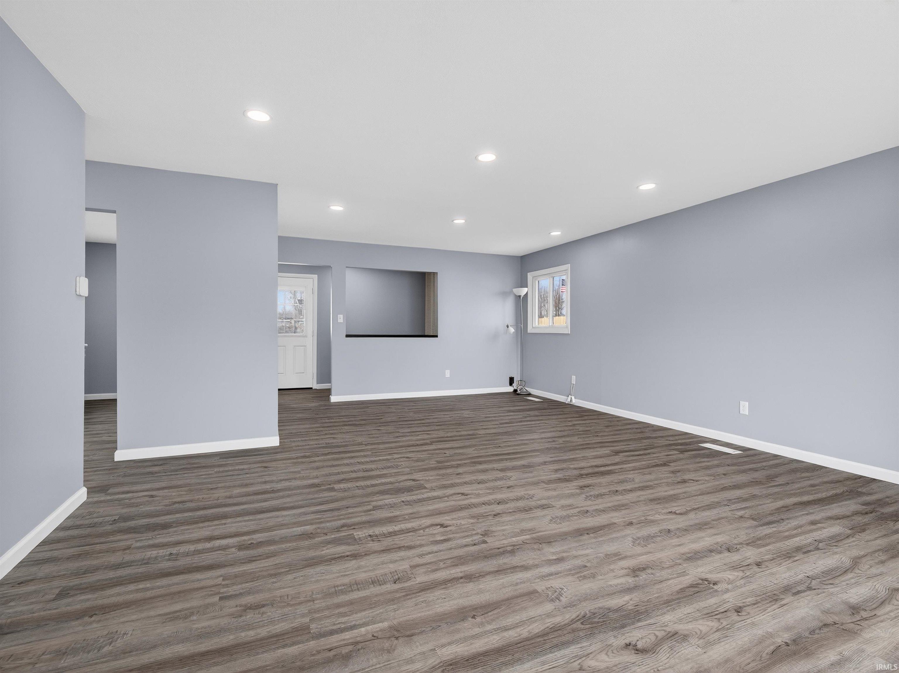 Unfurnished living room featuring recessed lighting and dark wood-style floors