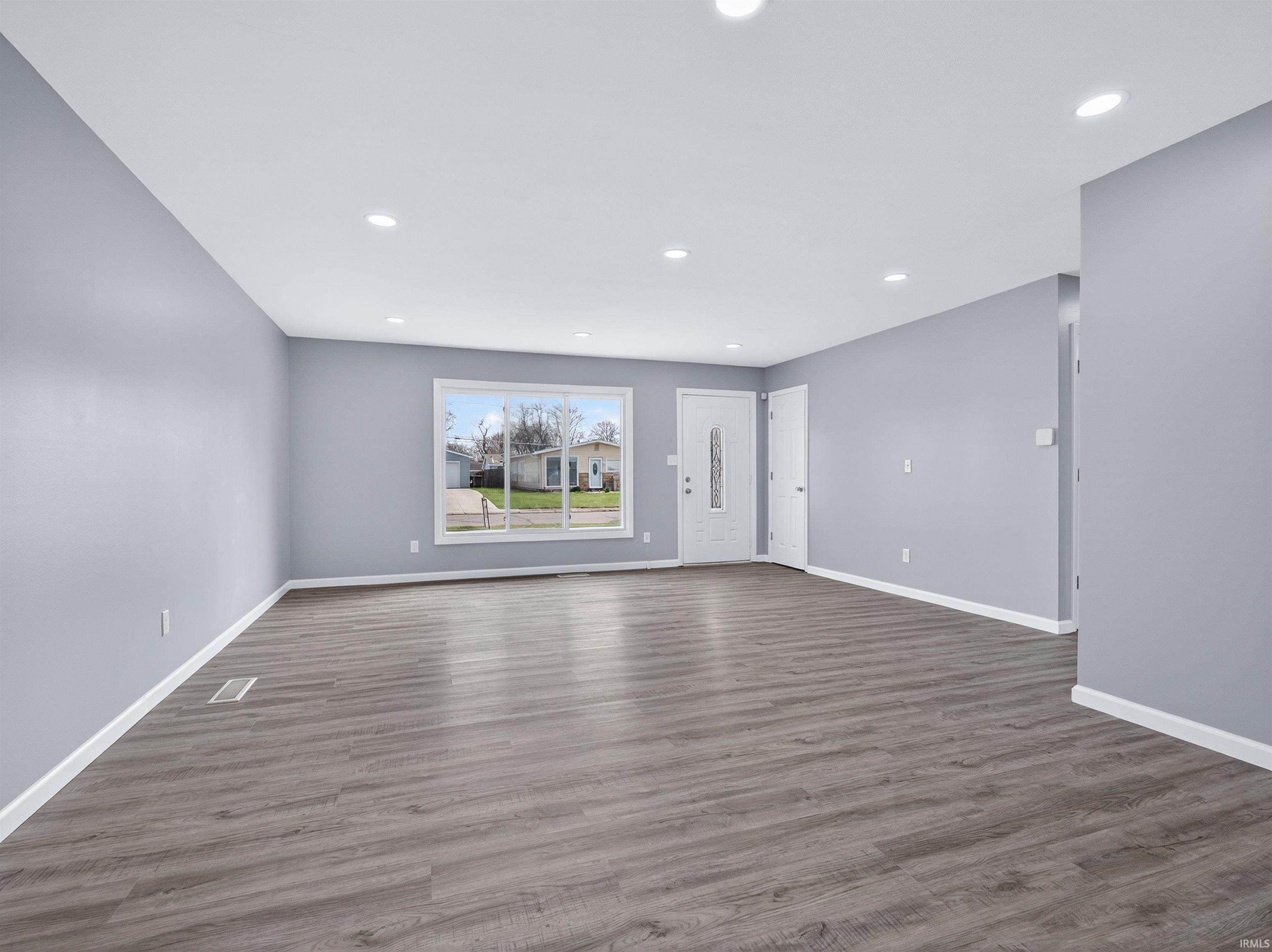 Unfurnished living room featuring dark wood finished floors and recessed lighting