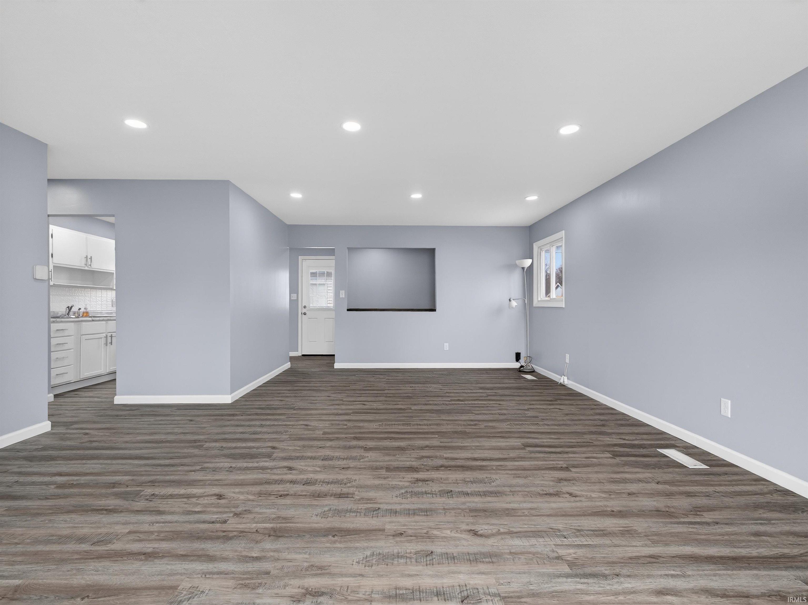 Unfurnished living room featuring dark wood-type flooring and recessed lighting