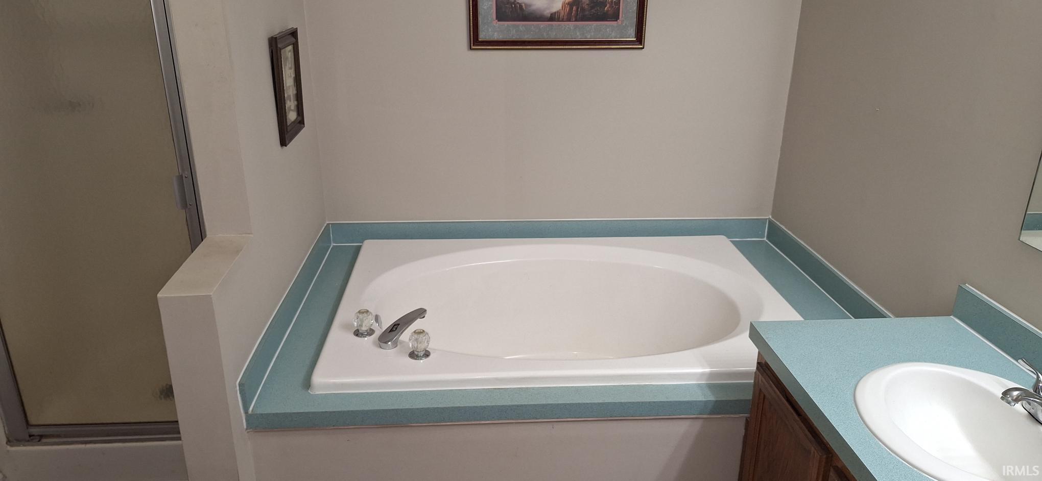 Full bathroom with vanity, a garden tub, and a shower stall