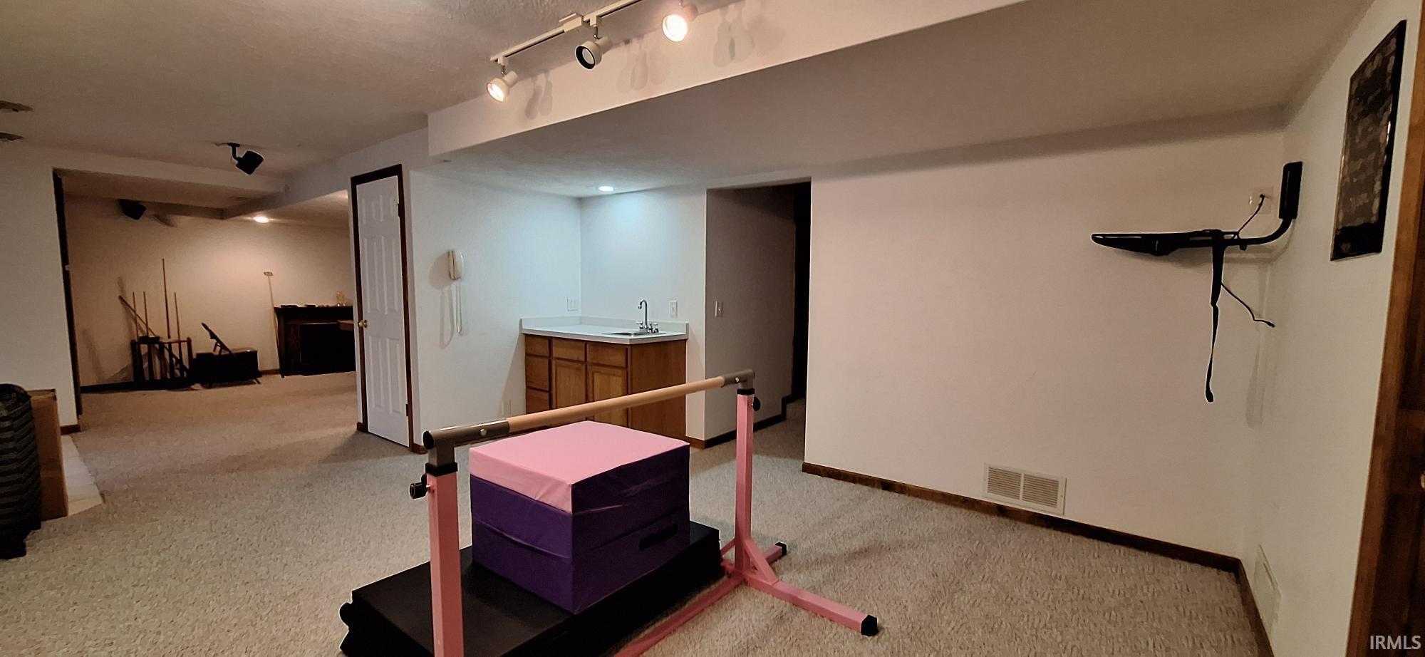 Finished below grade area featuring light carpet and baseboards