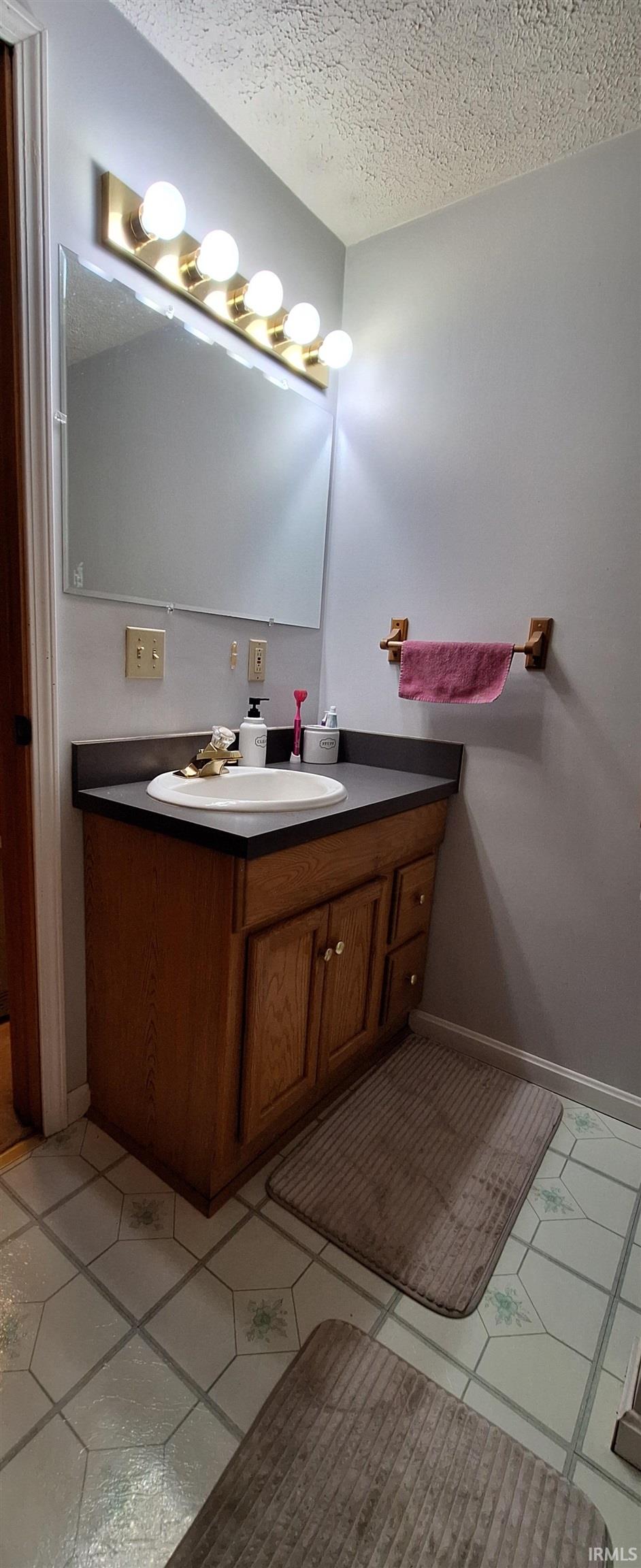 Bathroom with vanity, a textured ceiling, and light tile patterned floors