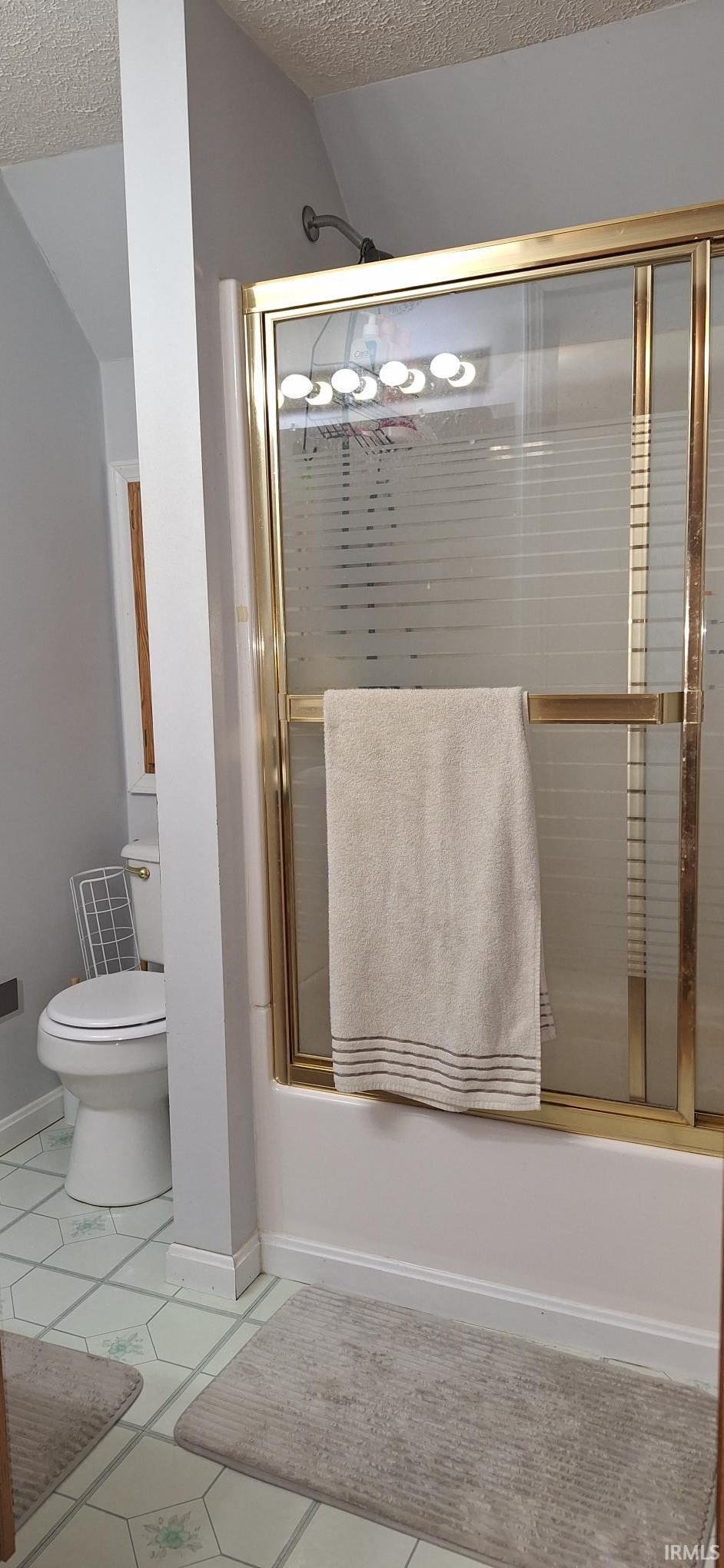 Bathroom featuring a textured ceiling and shower / bath combination with glass door