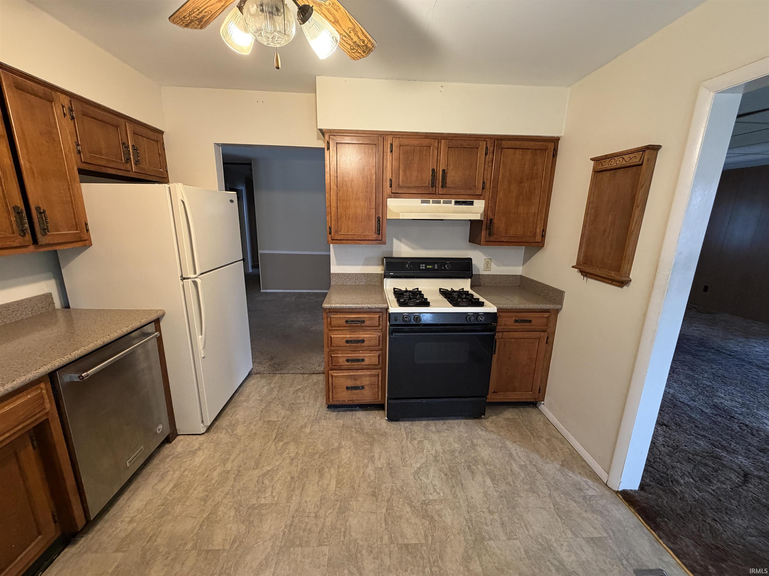 Kitchen featuring gas stove, ceiling fan, dishwasher, and wood finish cabinets