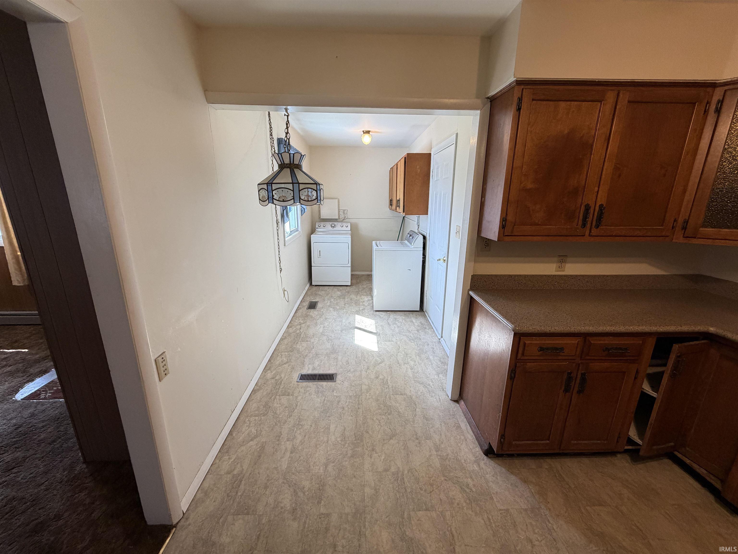 Laundry area featuring washer and clothes dryer, light wood-style flooring, and cabinet space