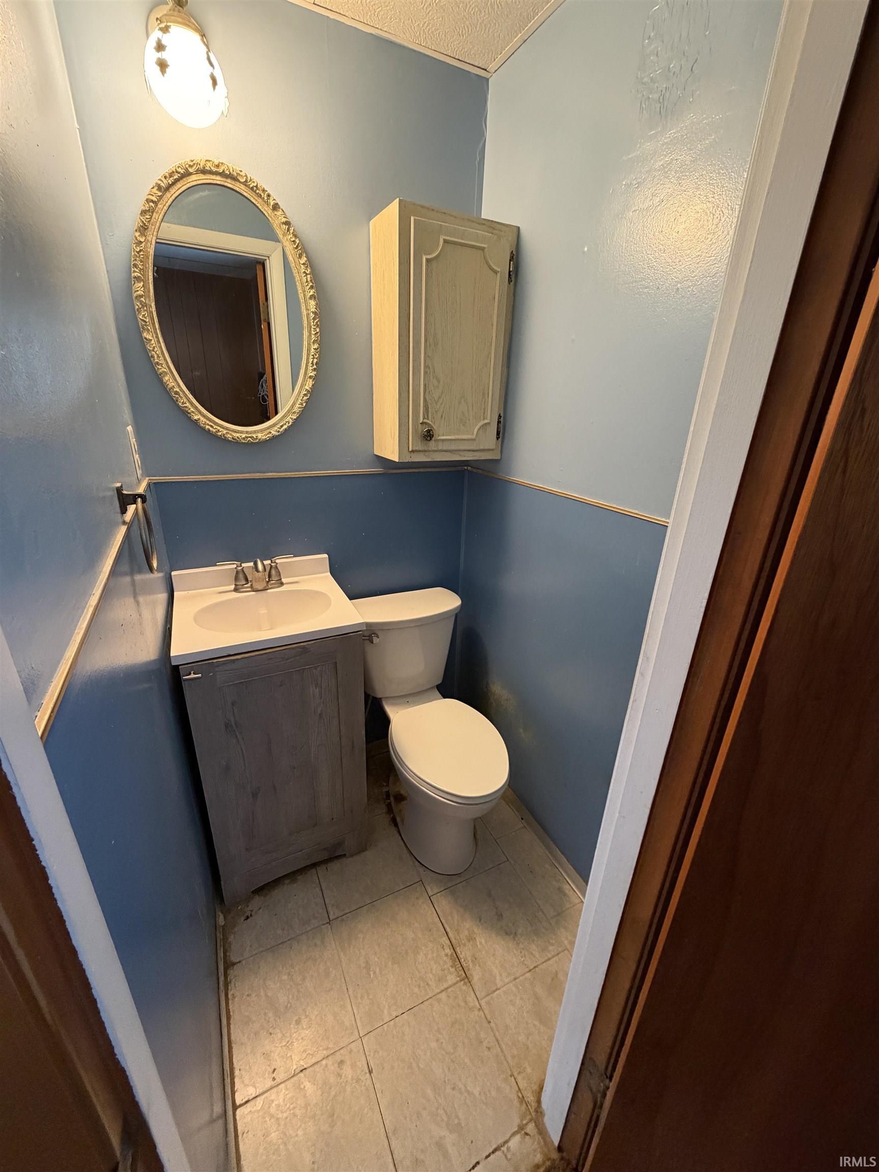 Half bath with vanity, light tile patterned floors, and a textured ceiling