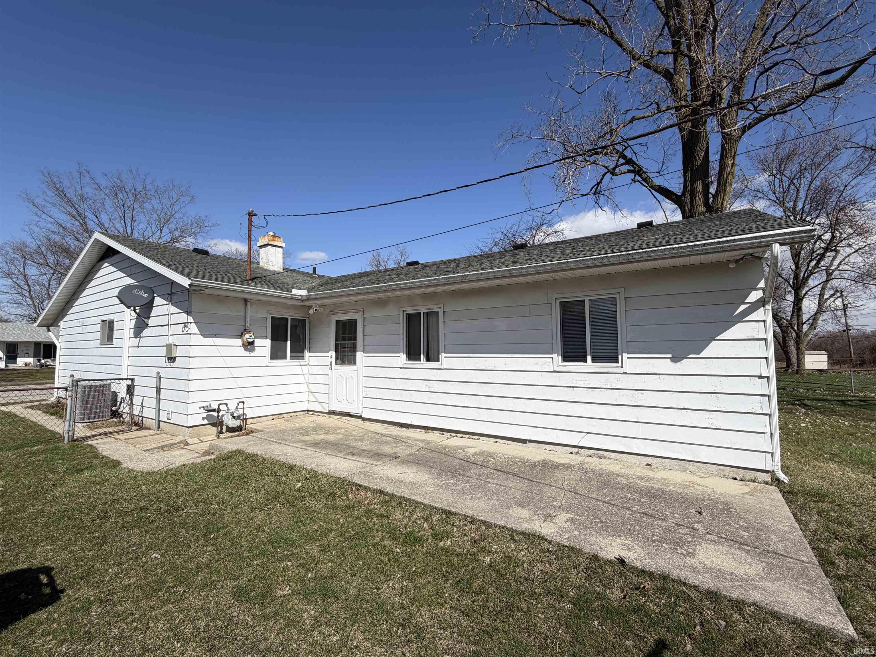 Rear view of house with a patio area, a yard, a chimney, and a shingled roof
