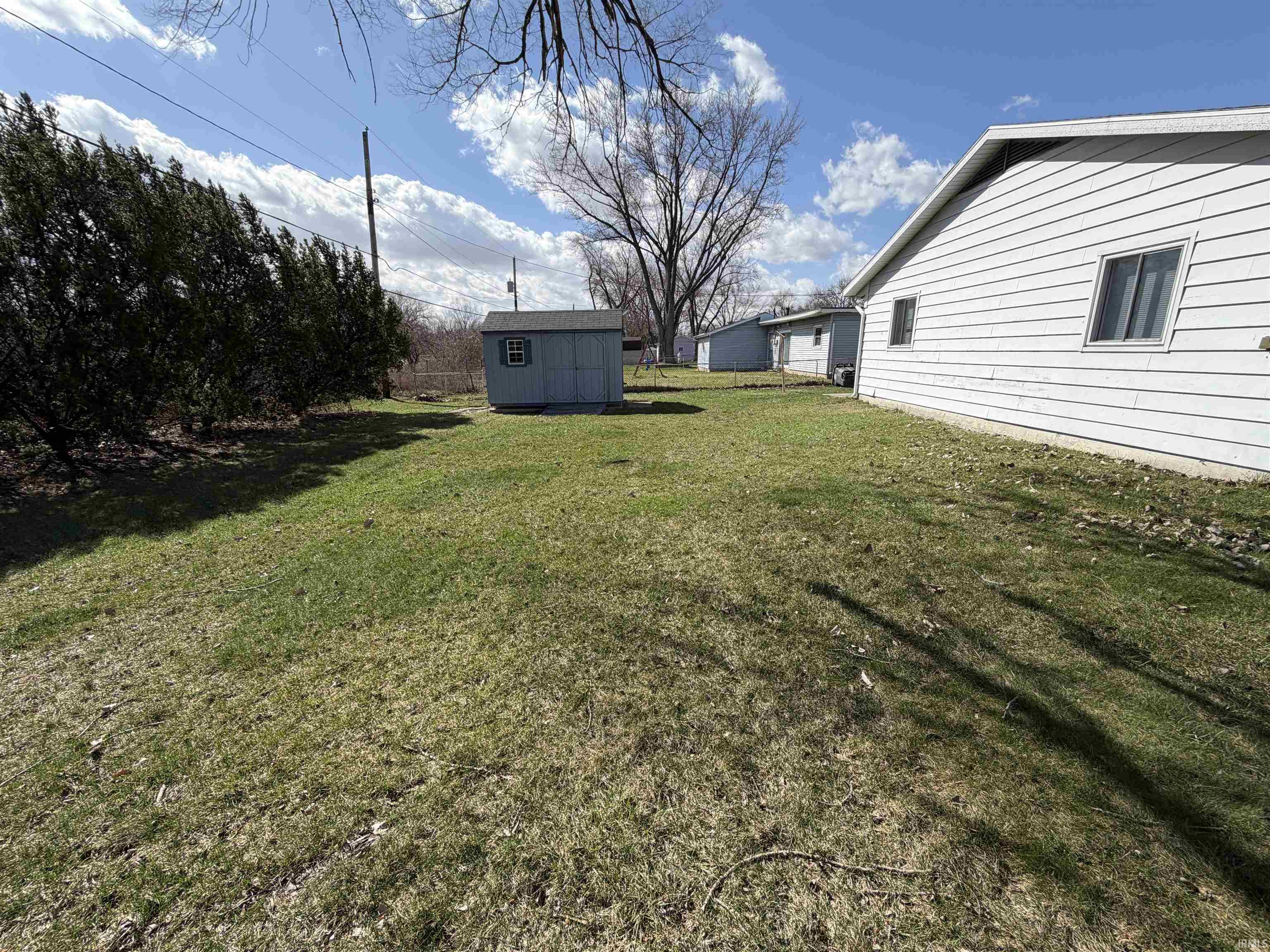 View of grassy yard featuring a storage unit