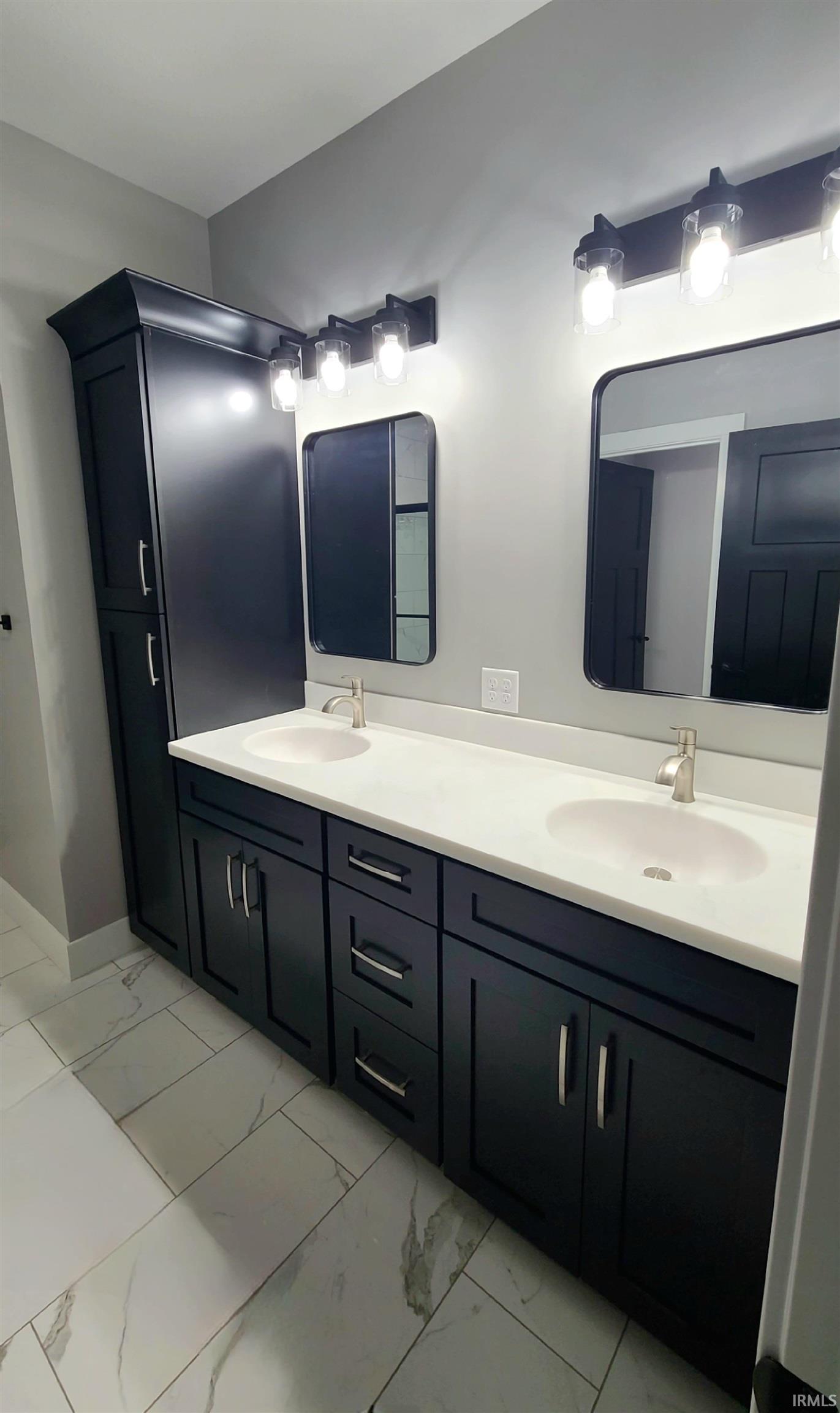 Full bath featuring double vanity and light marble finish floors