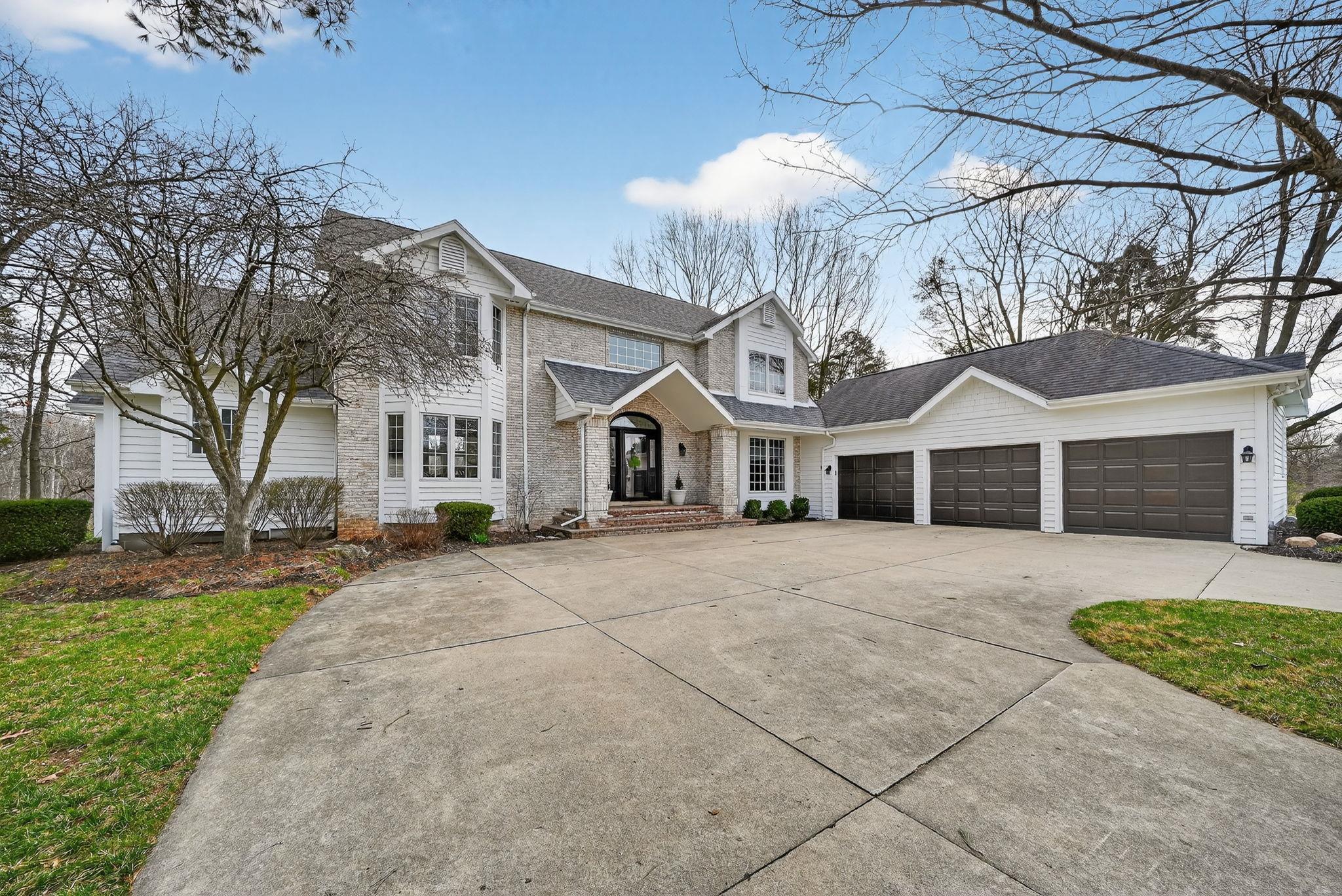 Traditional home featuring driveway, a shingled roof, and an attached garage