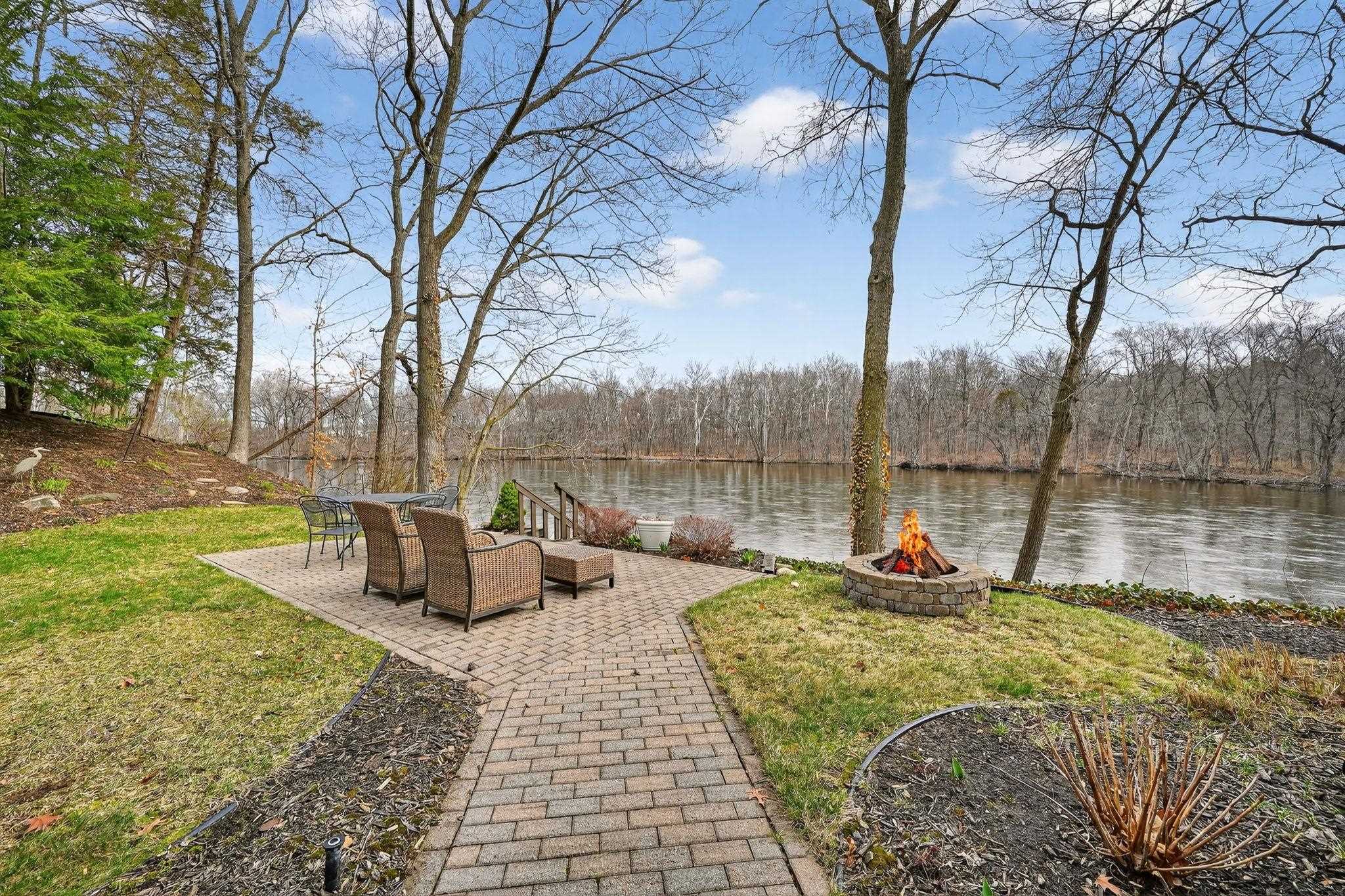 View of grassy yard featuring an outdoor fire pit, a water view, and a patio