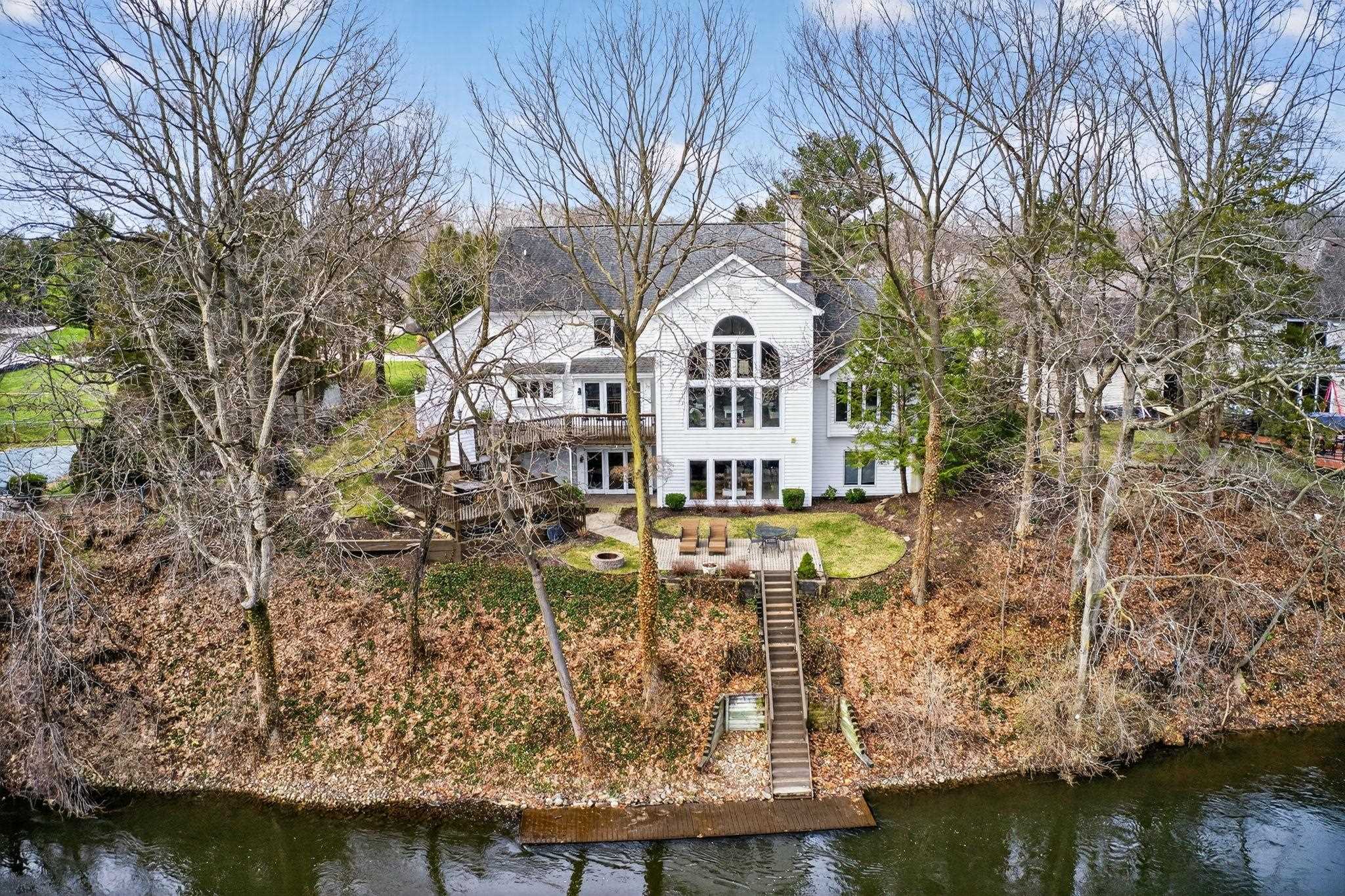 Back of property with a water view, a patio, french doors, and view of scattered trees