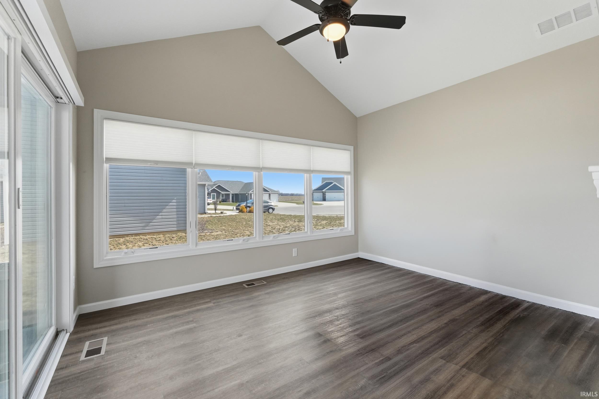 Spare room featuring ceiling fan, dark wood finished floors, and a high ceiling