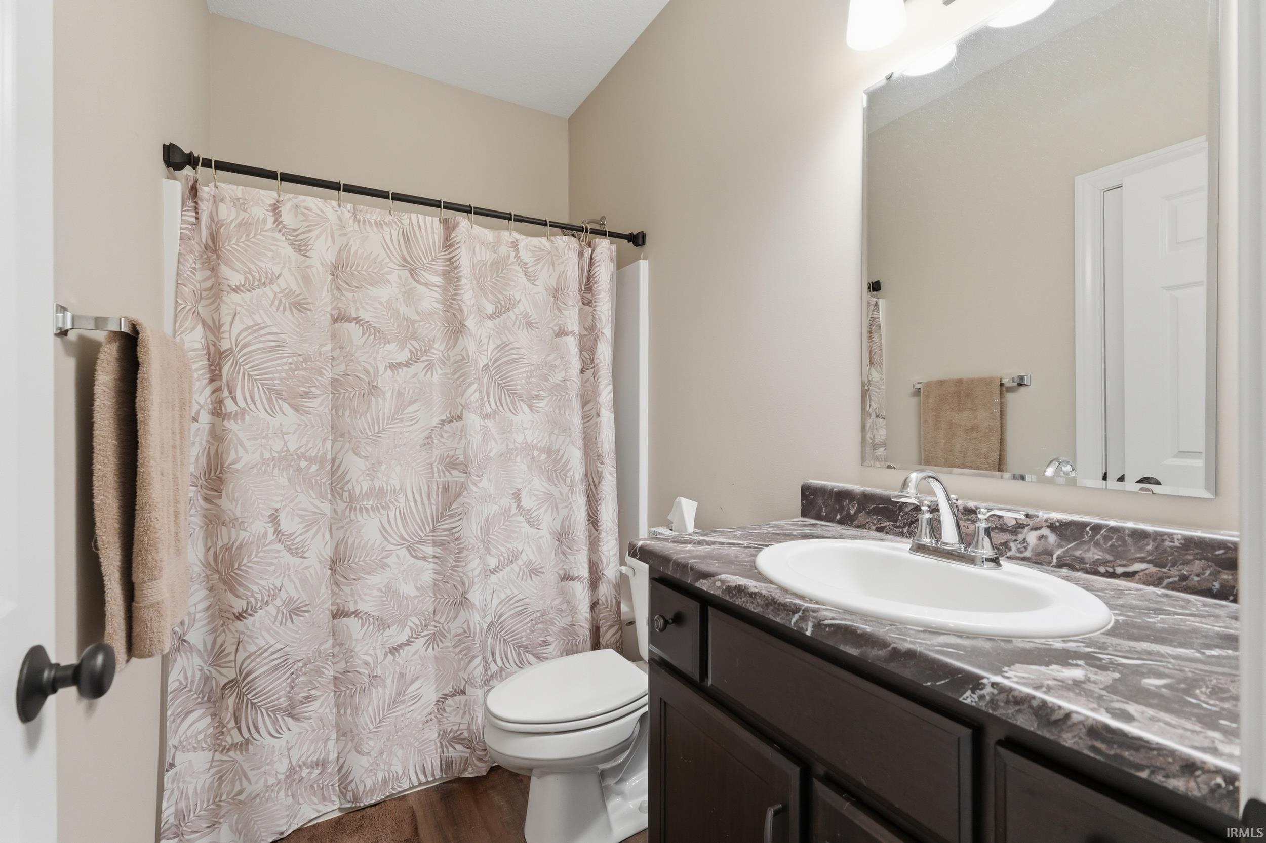 Full bath with vanity, a shower with curtain, and dark wood finished floors