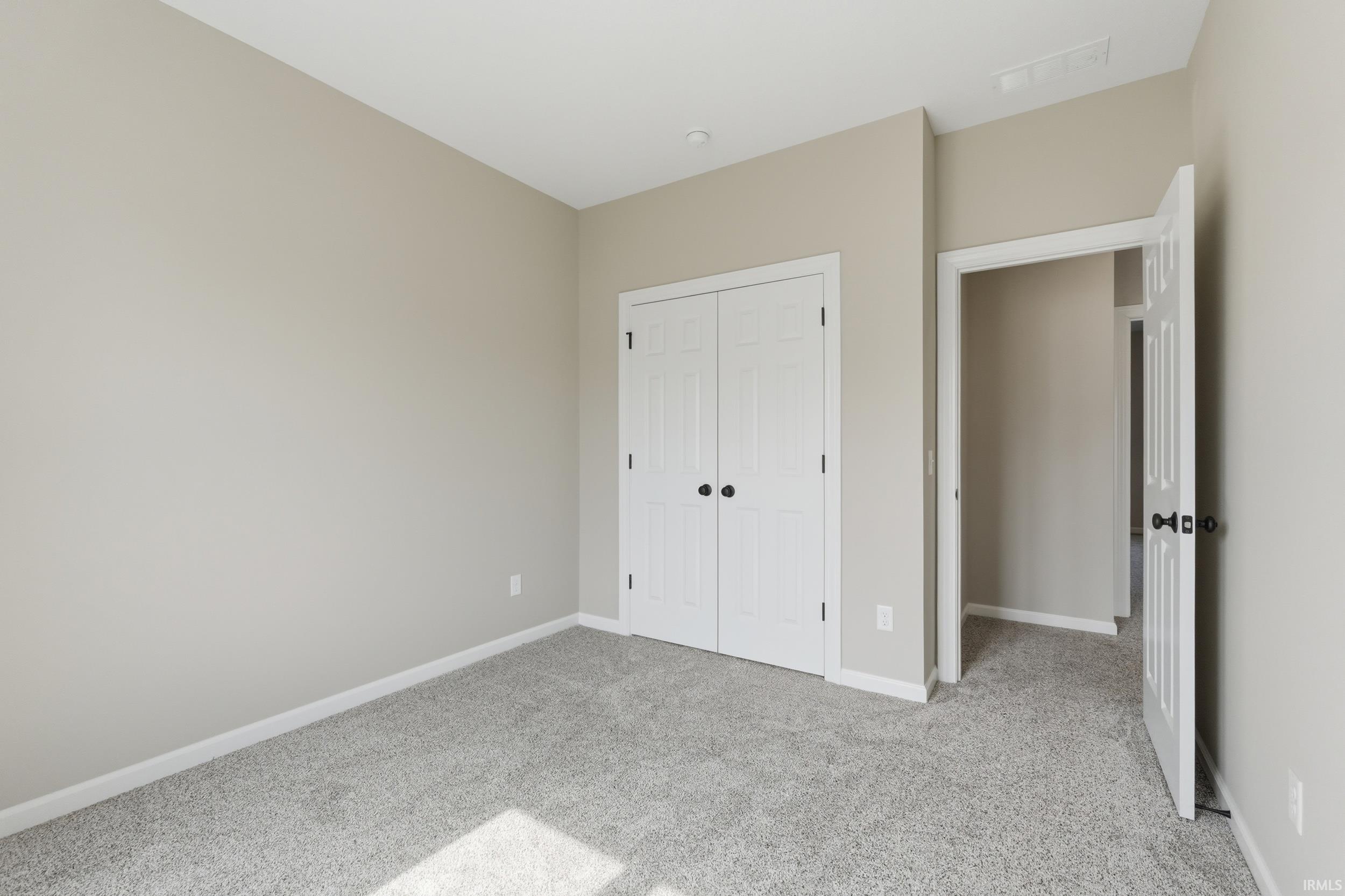 Unfurnished bedroom with light carpet and a closet