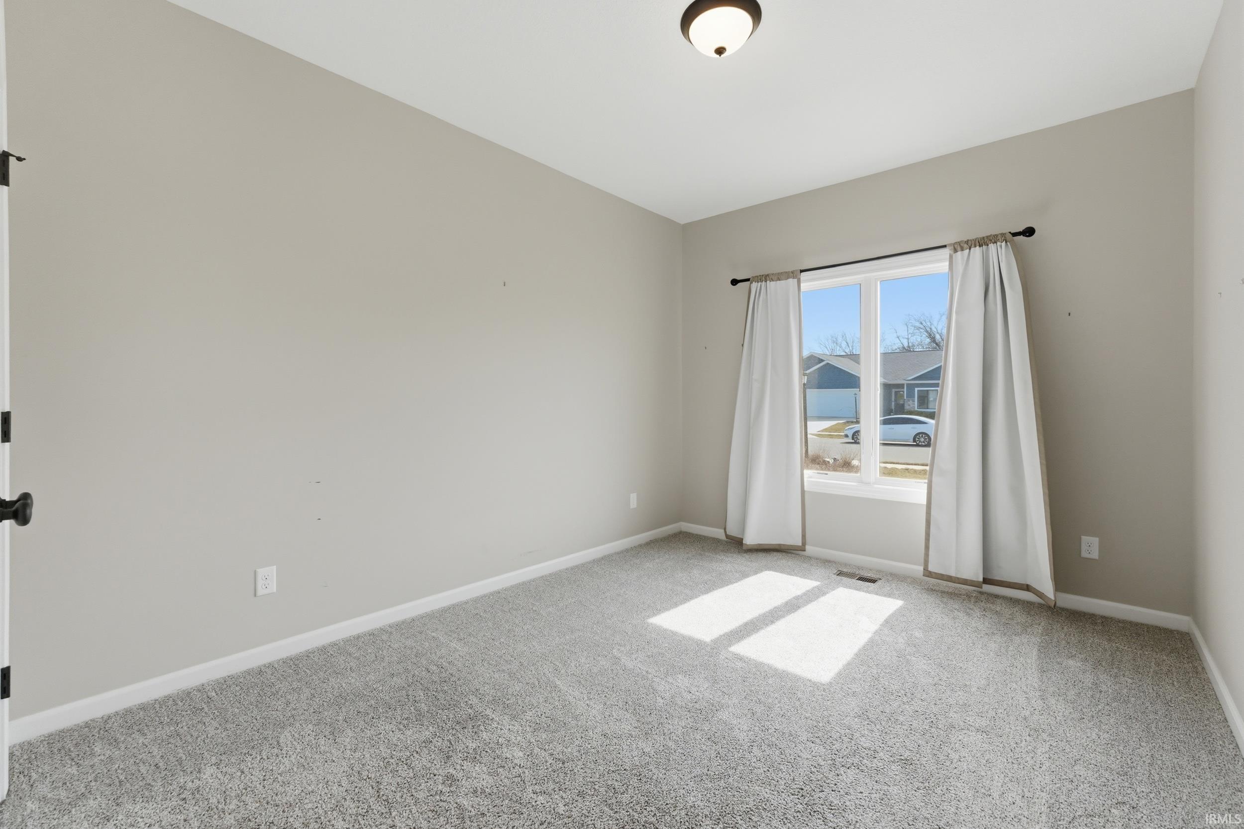Unfurnished room featuring baseboards and light carpet