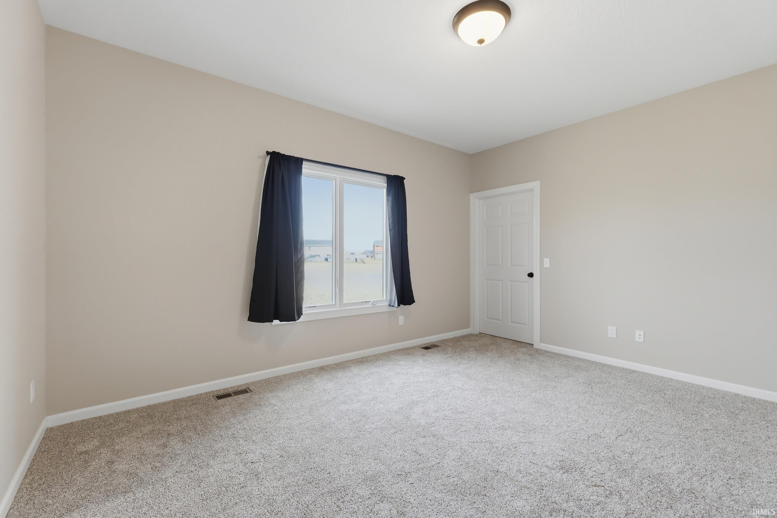 Unfurnished room featuring baseboards and light carpet
