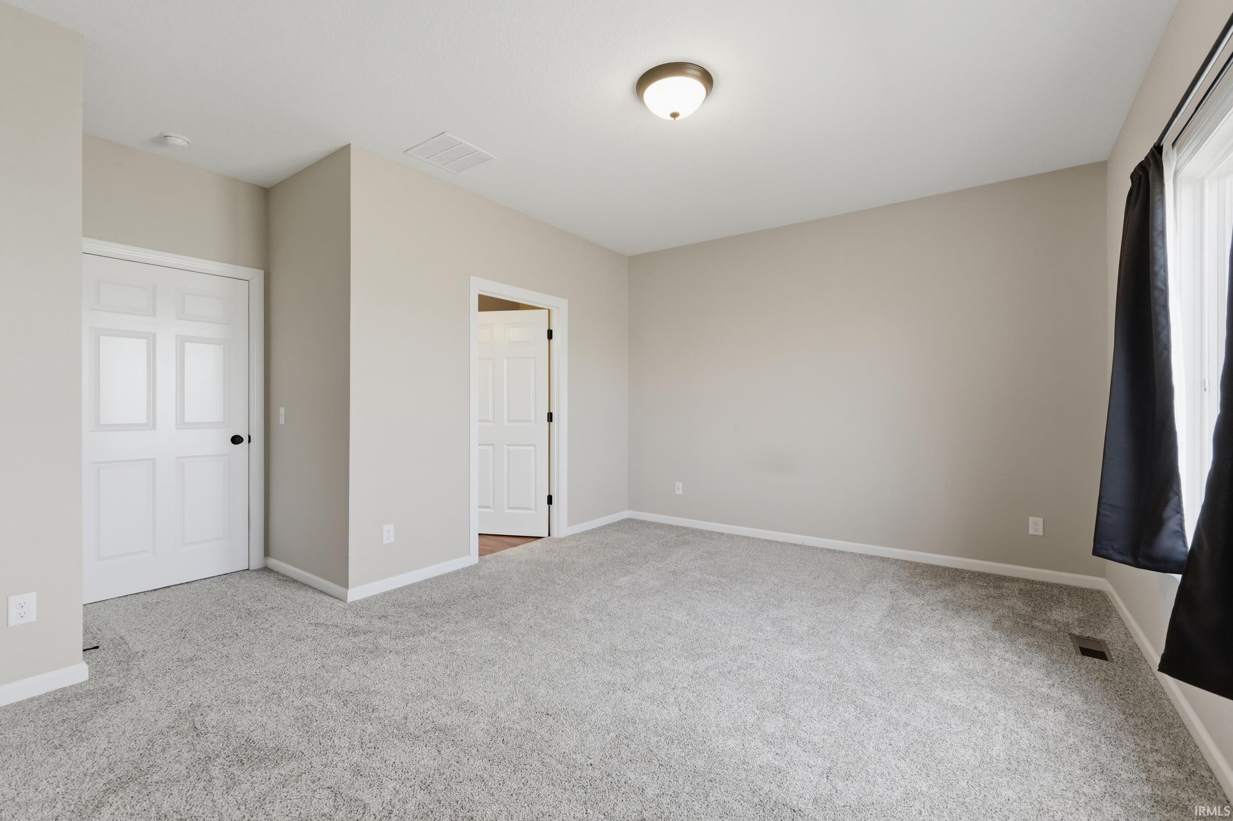 Unfurnished bedroom featuring baseboards and light carpet