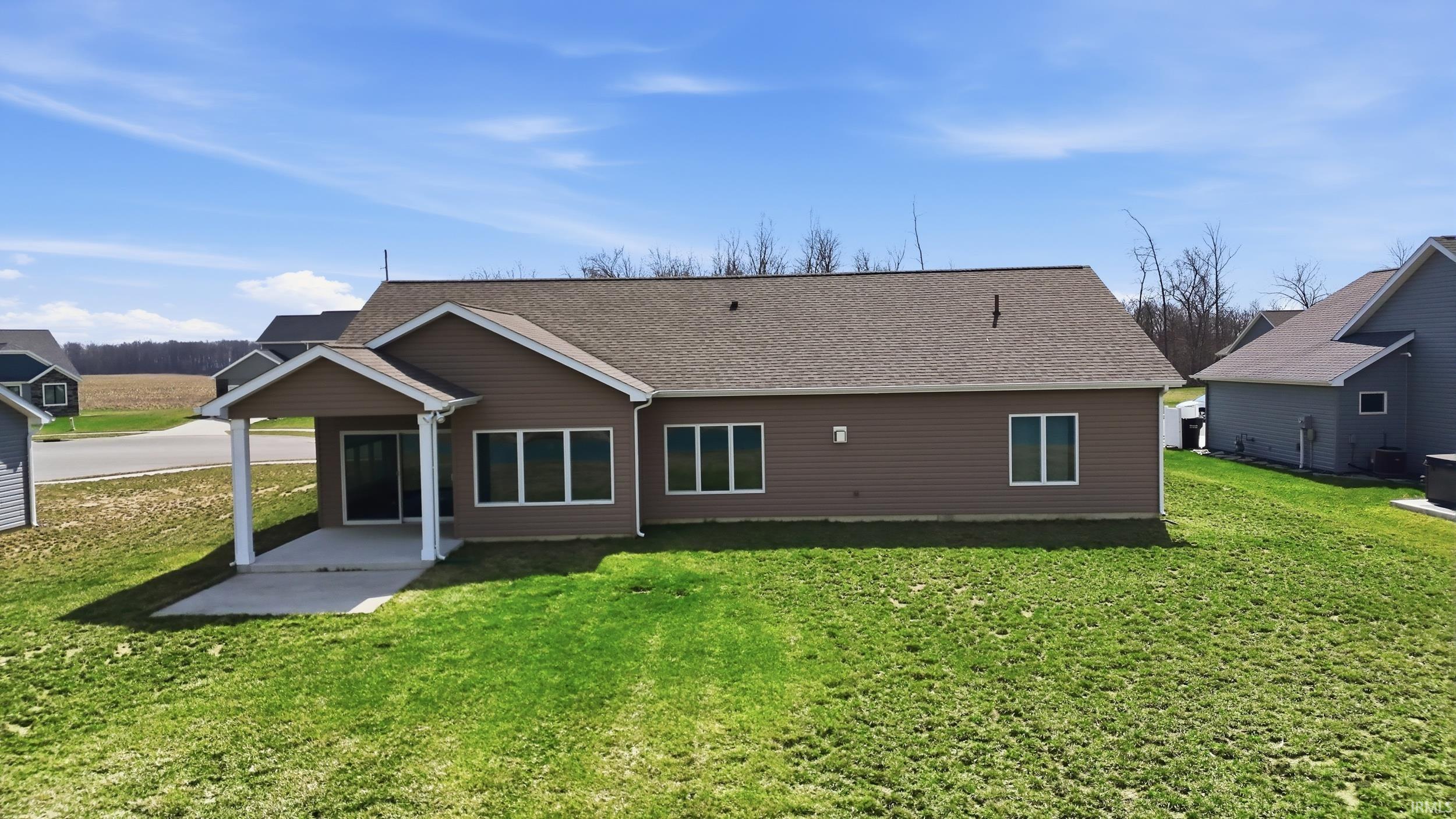 Back of house featuring a yard, roof with shingles, and a patio area