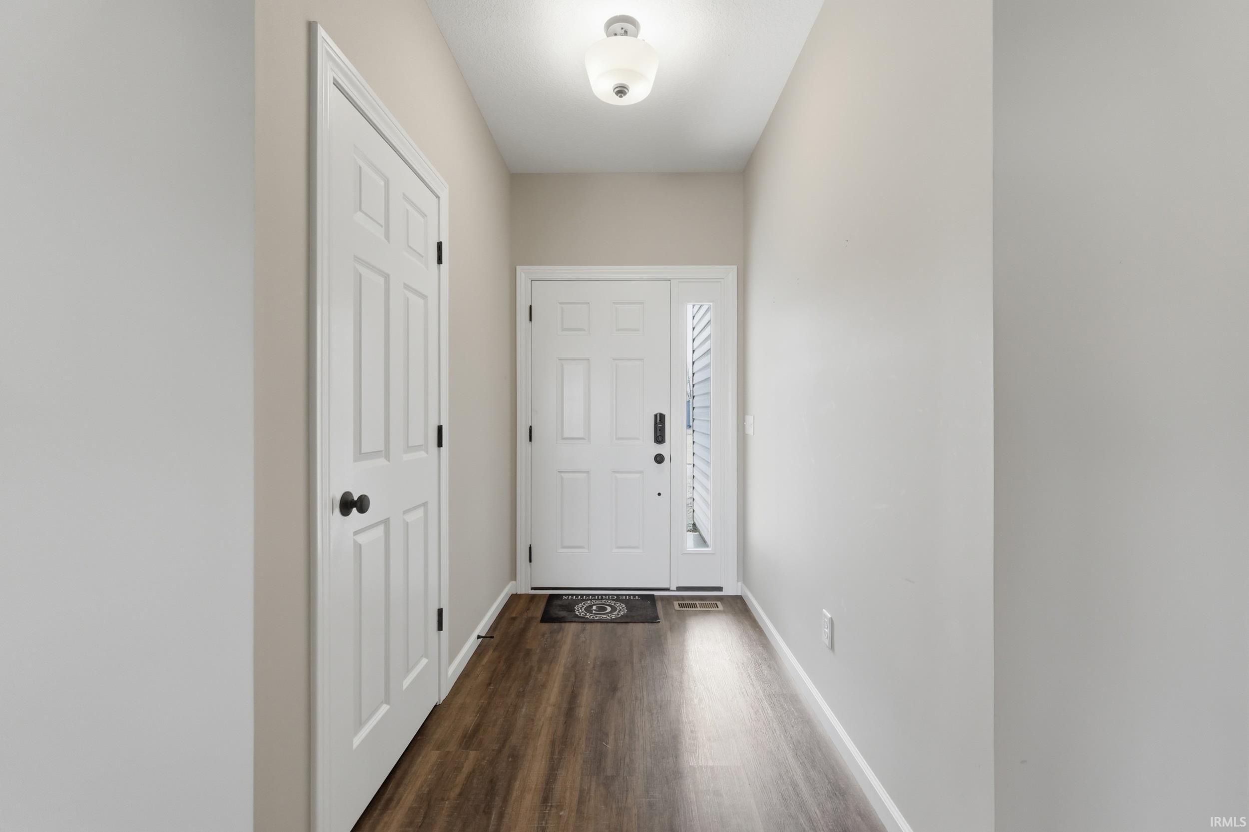 Doorway with wood finished floors and baseboards