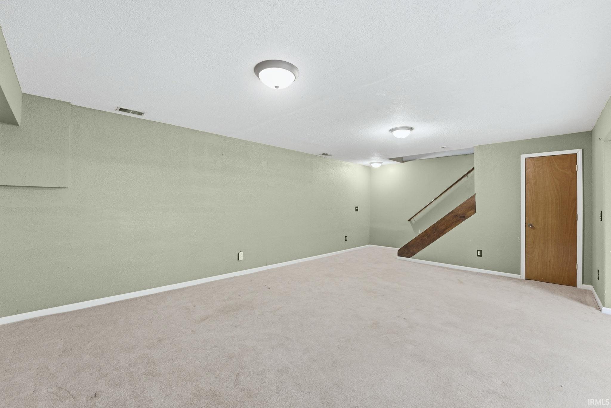 Finished basement featuring stairway and light carpet