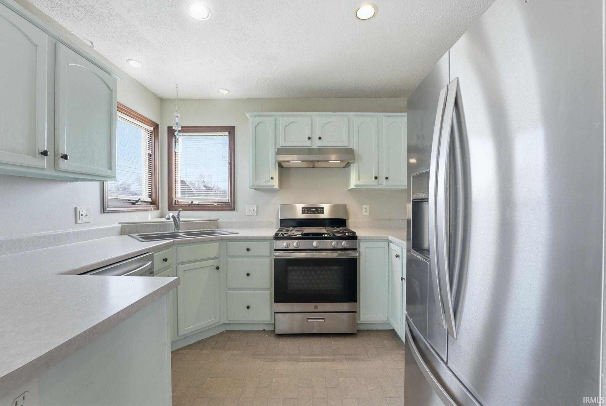 Kitchen with stainless steel appliances, light countertops, and recessed lighting