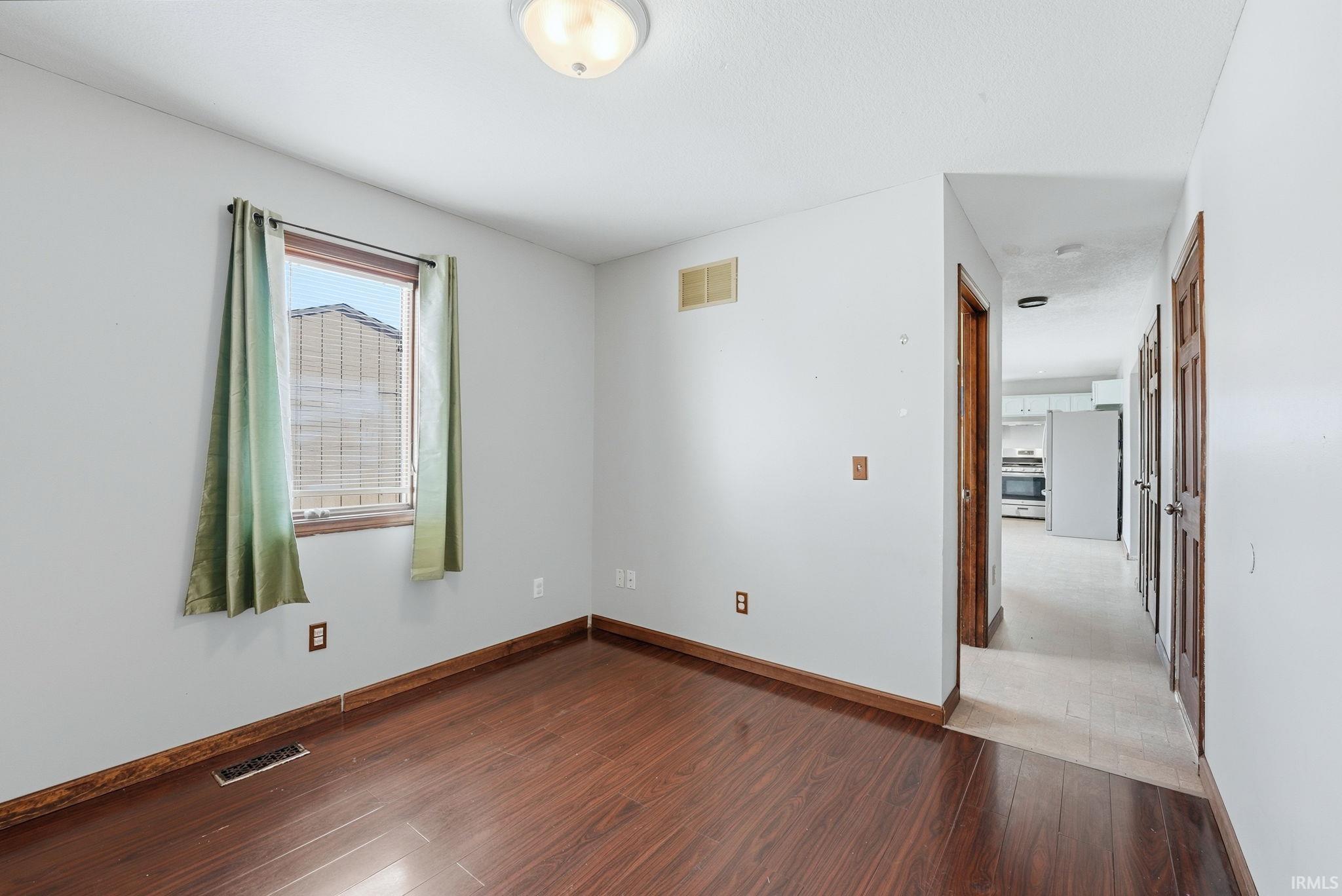 Empty room featuring hardwood / wood-style flooring and baseboards
