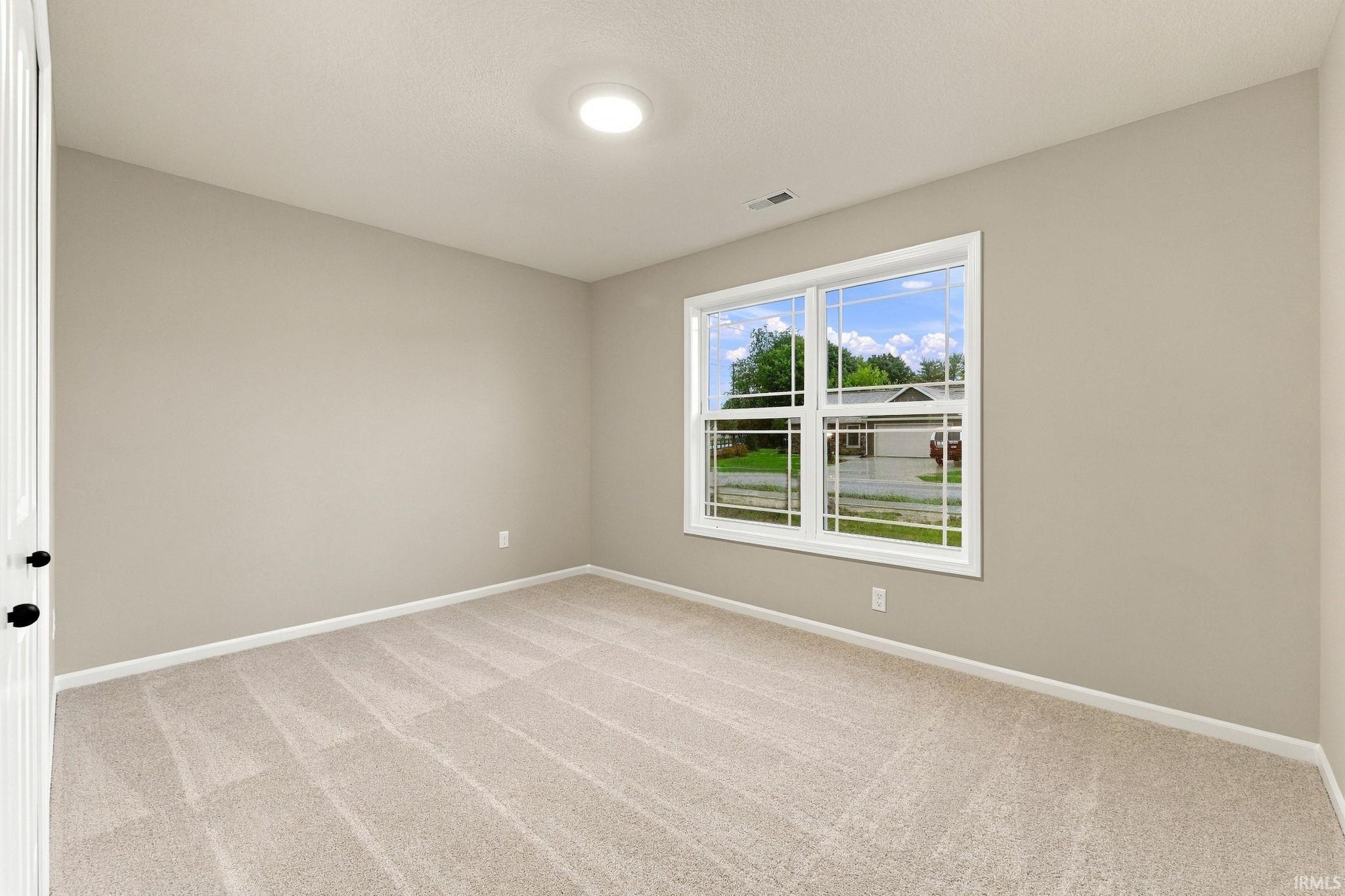 Neutral wall color, light-toned carpet, recessed ceiling light, and a double-pane window