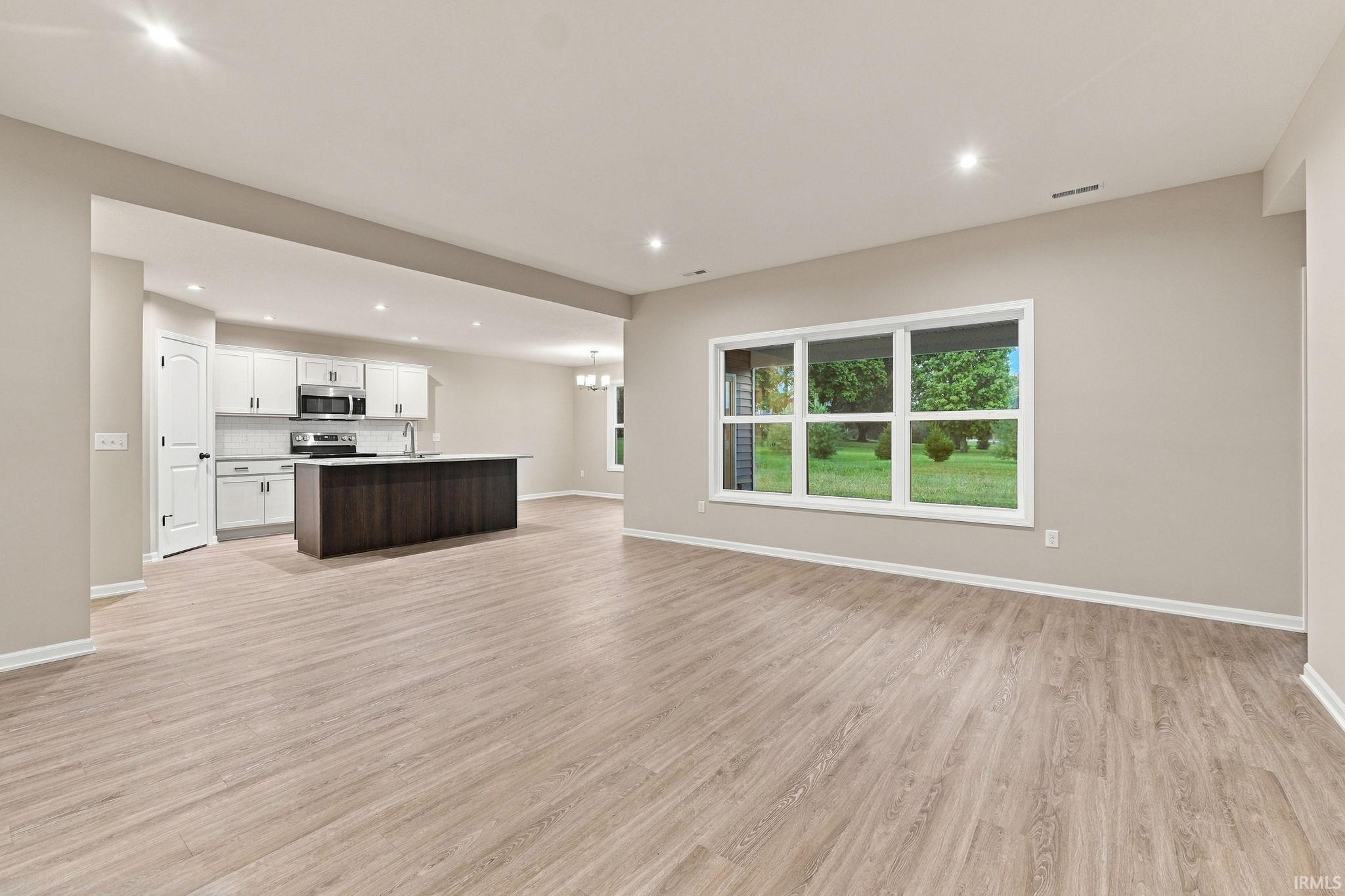 Open-concept living space featuring wood-finish flooring, recessed lighting, and a multi-pane window