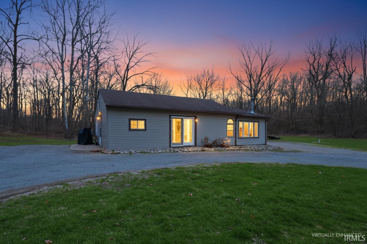 View of front of property featuring curved driveway and a lawn