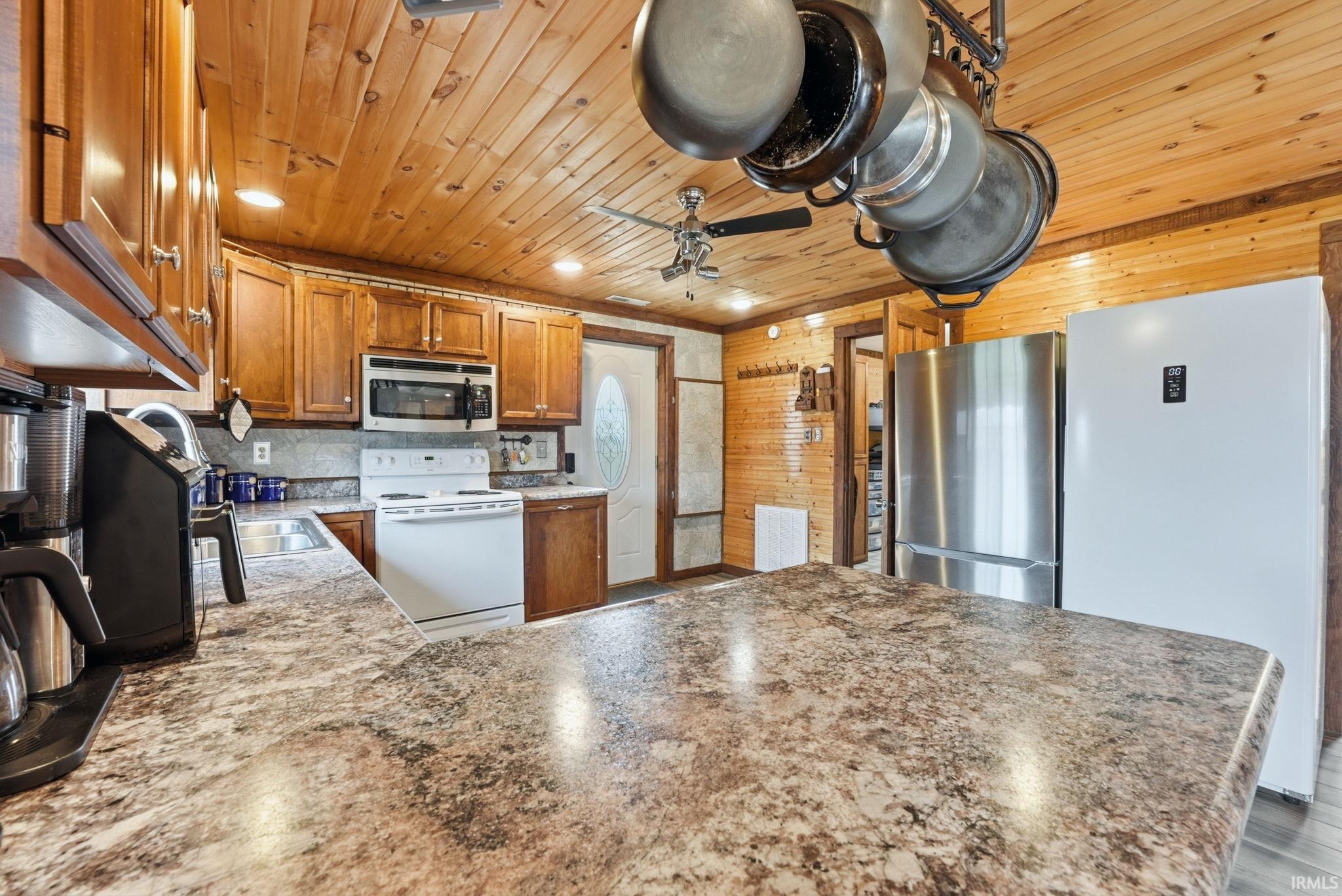 Kitchen with a peninsula, stainless steel appliances, wood finish cabinetry, a ceiling fan, and wooden ceiling