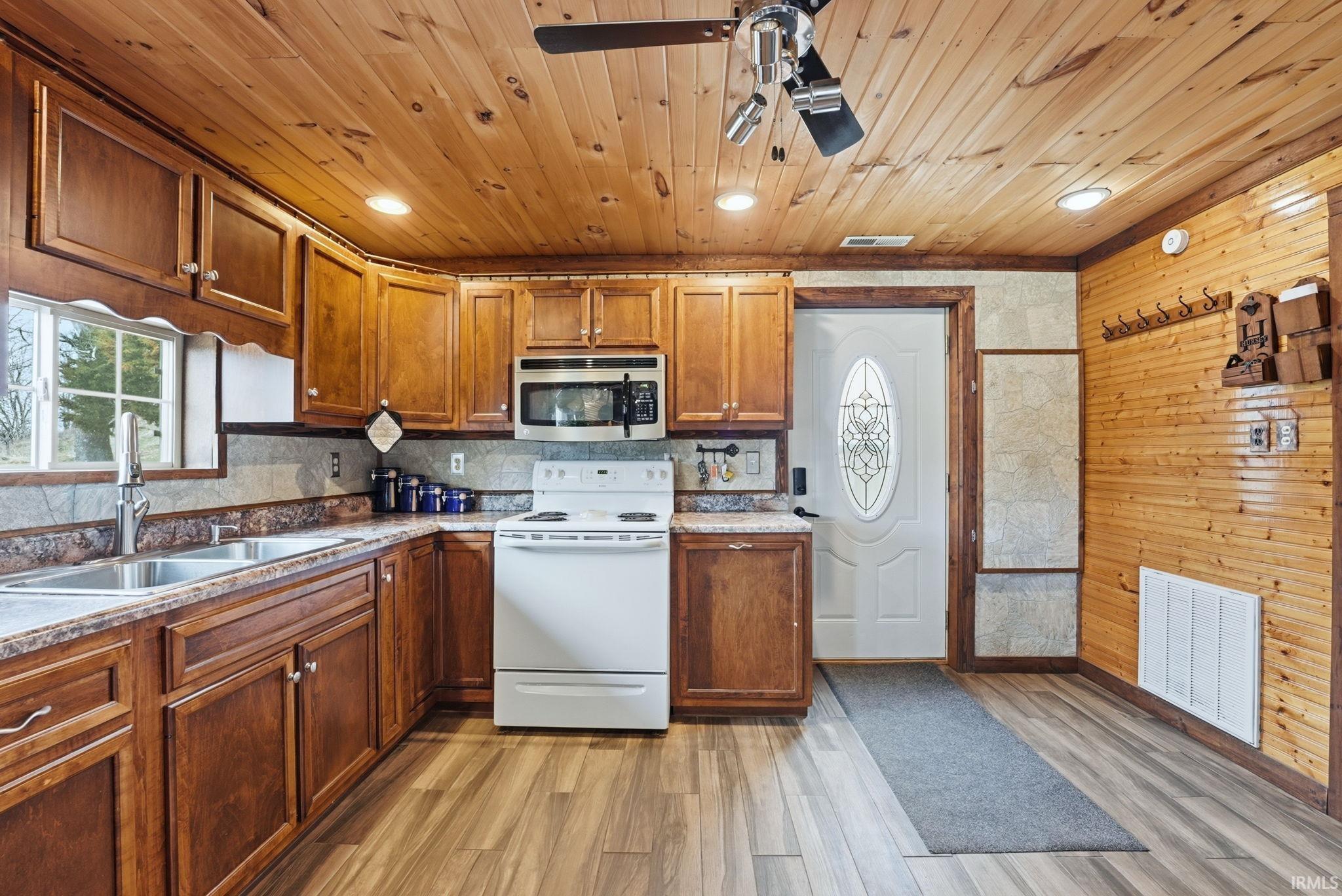 Kitchen featuring electric stove, a ceiling fan, stainless steel microwave, wood finish cabinets, and light wood-style flooring