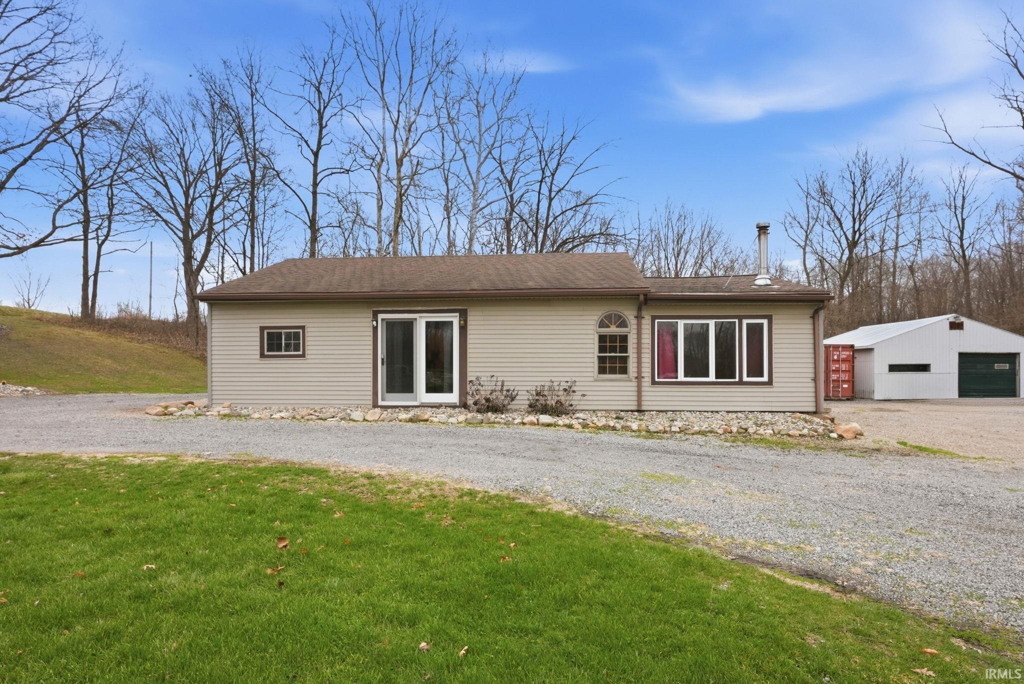View of front facade featuring an outbuilding, a detached garage, driveway, and a front yard