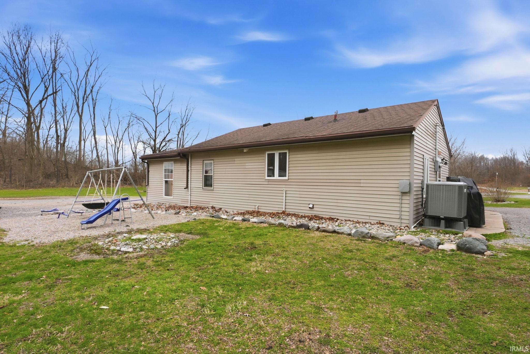 Back of property with a playground and a yard
