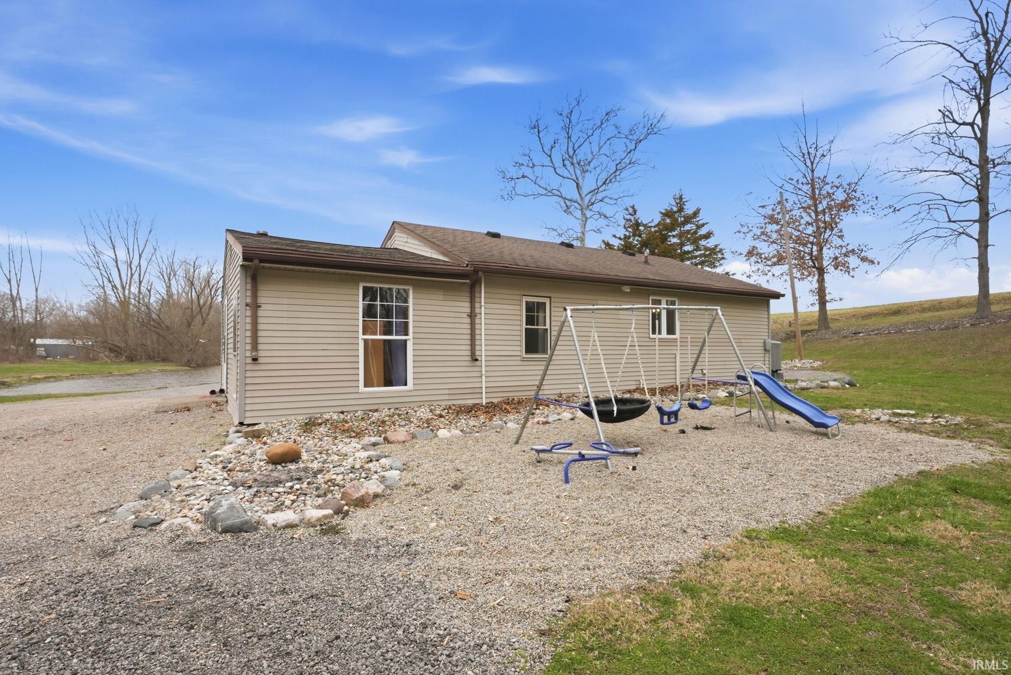 Rear view of property featuring a playground and roof with shingles