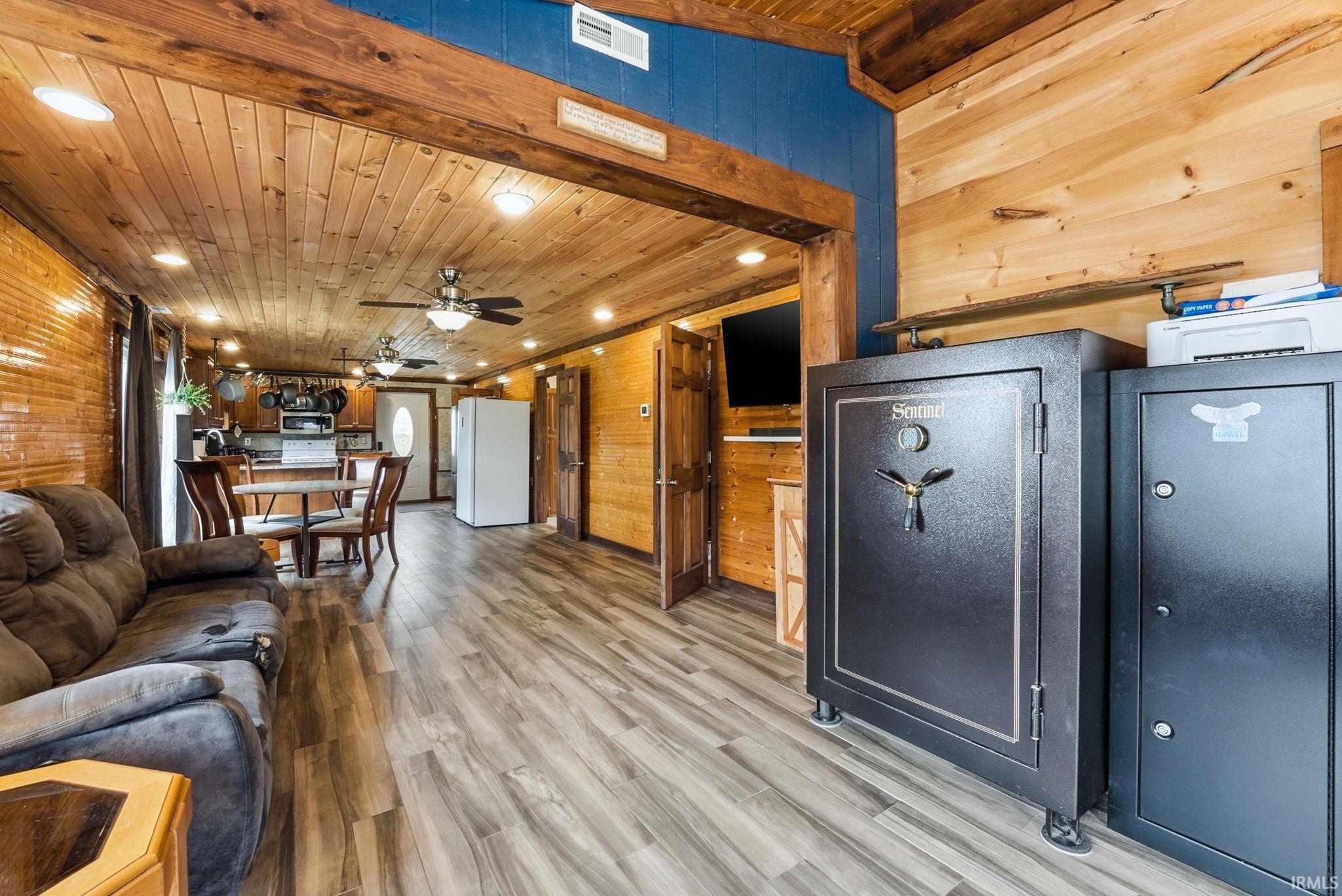 Living area featuring wood walls, light wood-style floors, recessed lighting, wood ceiling, and ceiling fan