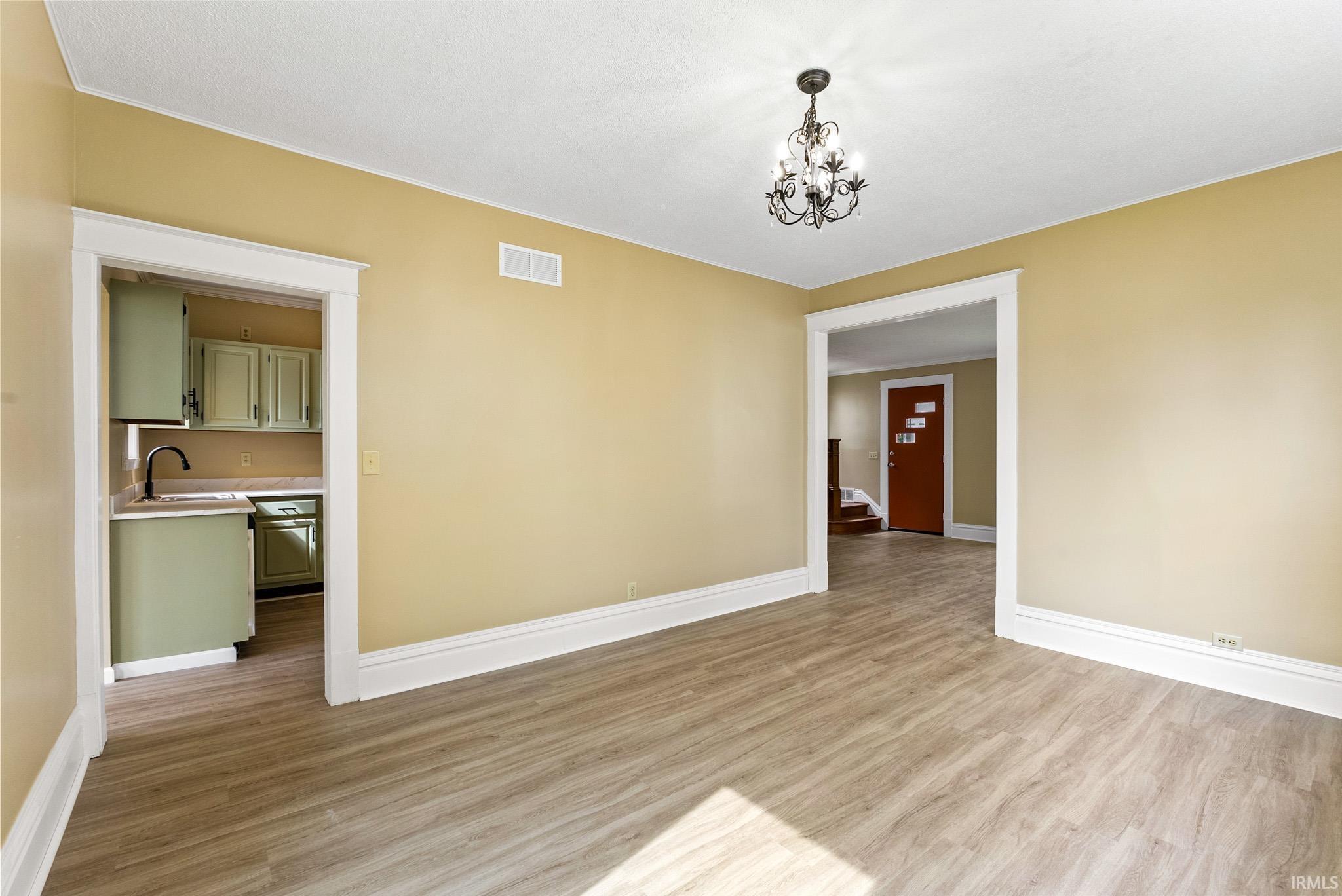 Empty room with light wood finished floors and hanging lights