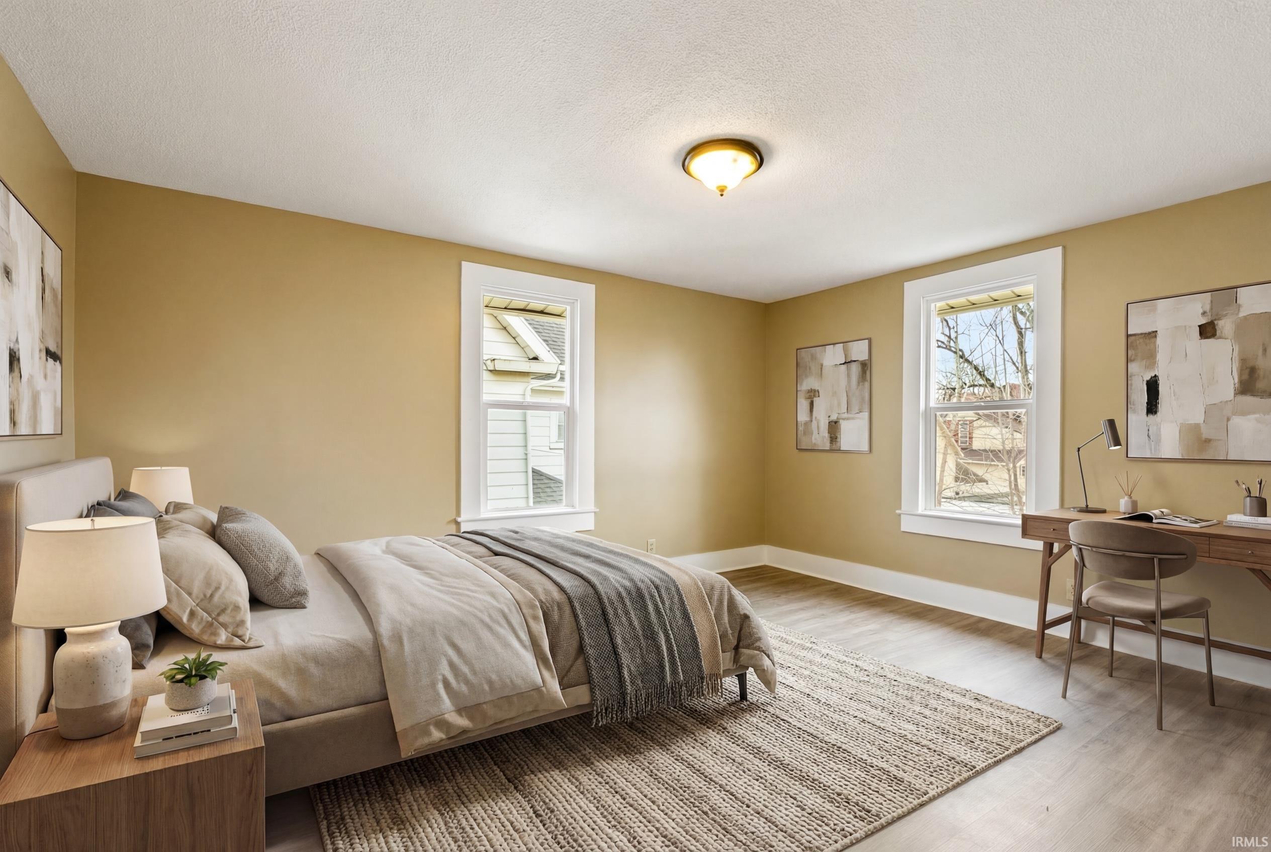 Bedroom with light wood-type flooring, an office area, and a textured ceiling