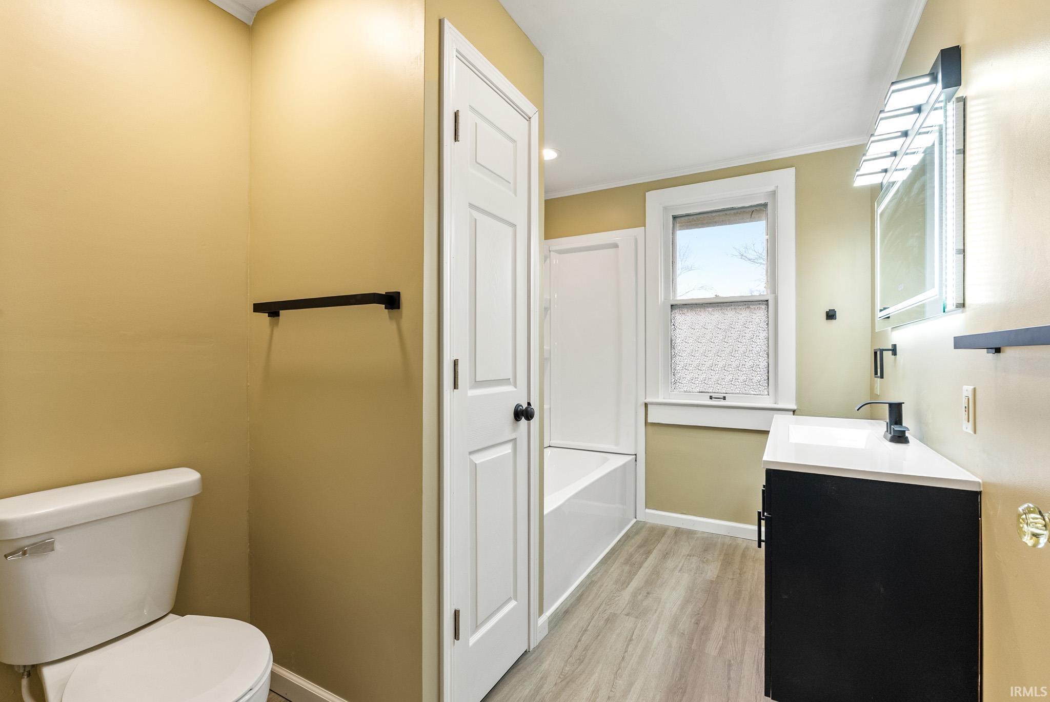 Bathroom featuring vanity, ornamental molding, light wood-style floors, recessed lighting, and bathtub / shower combination