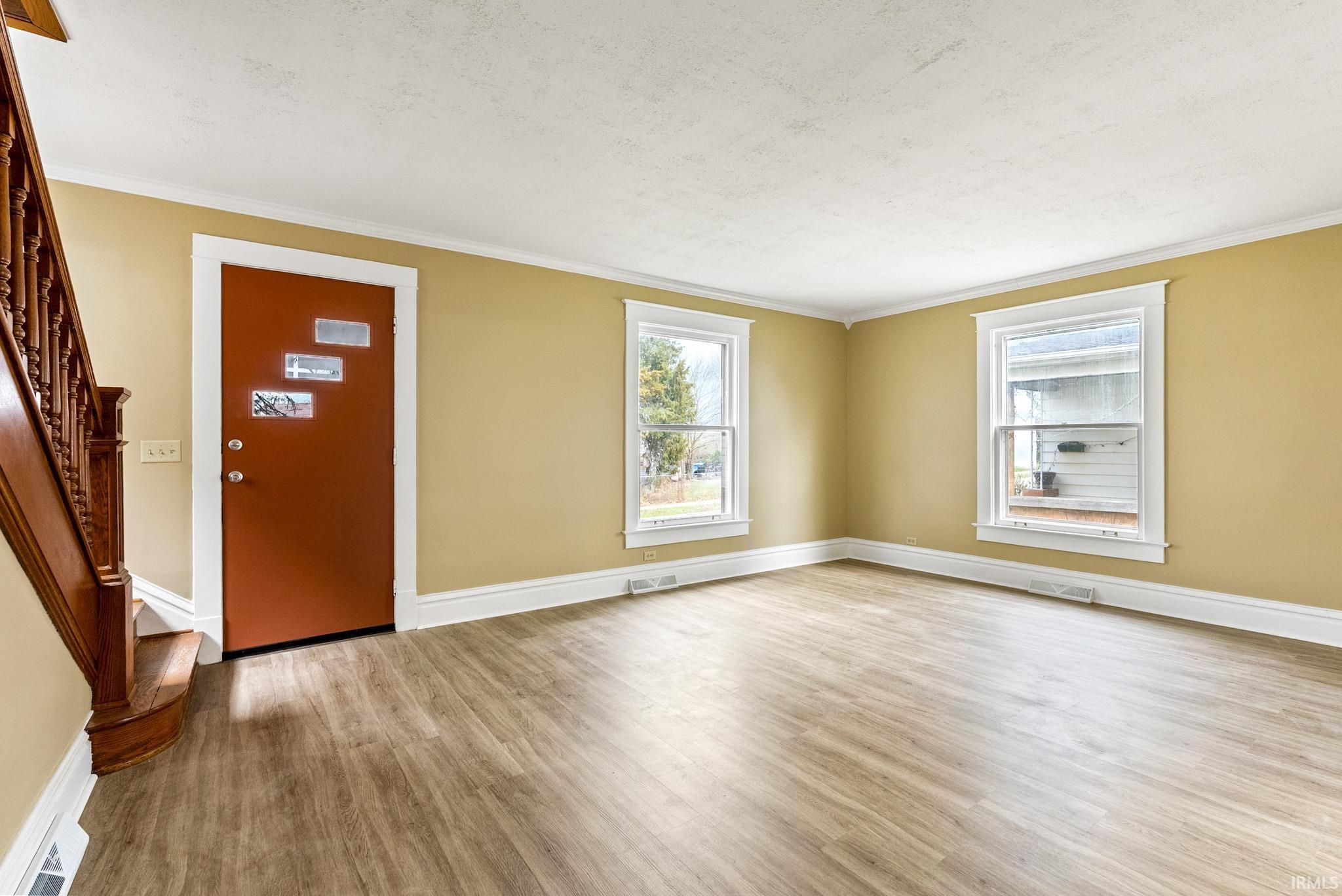 Entrance foyer with light wood-style floors, plenty of natural light, and crown molding