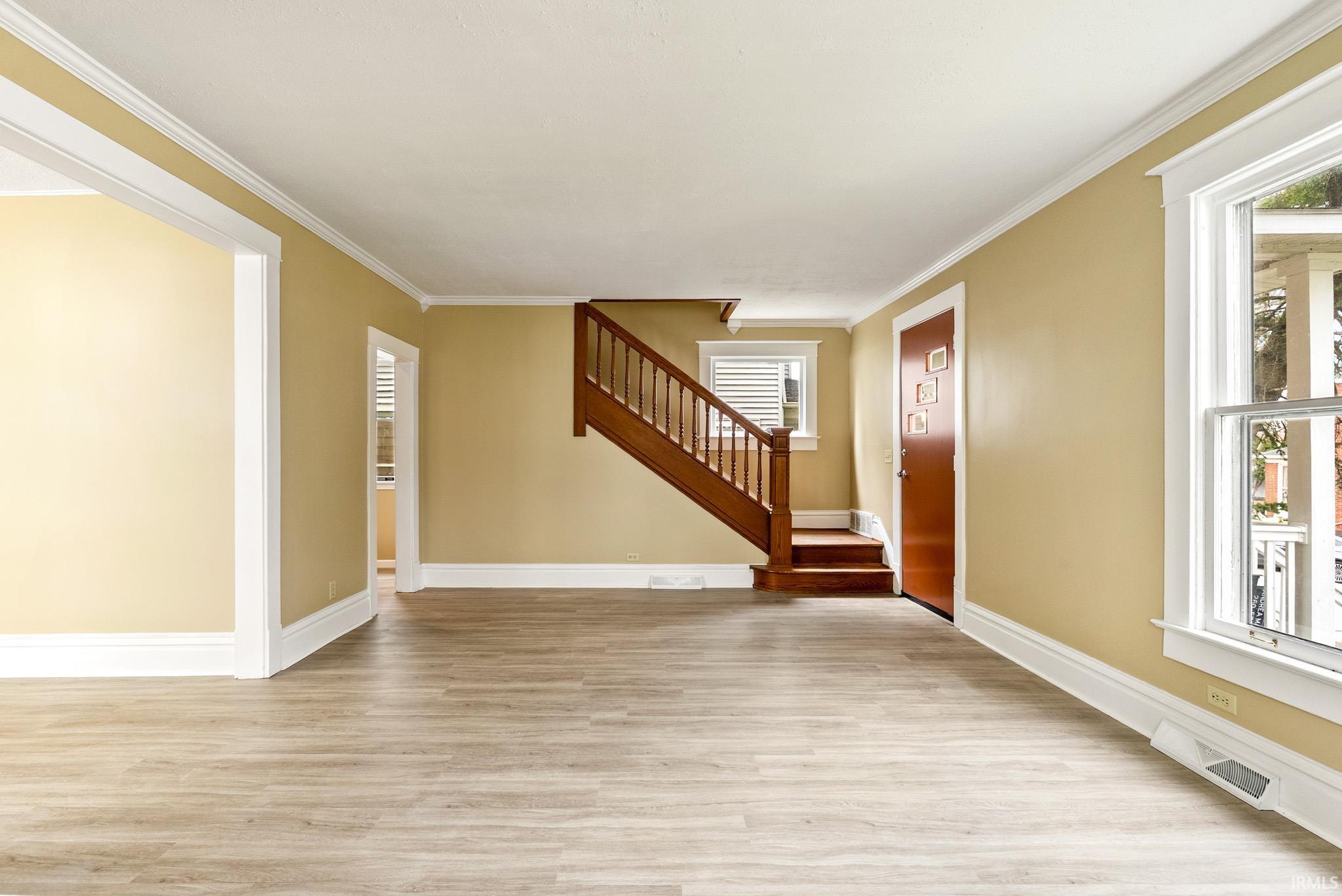 Entryway featuring light wood-style flooring and crown molding