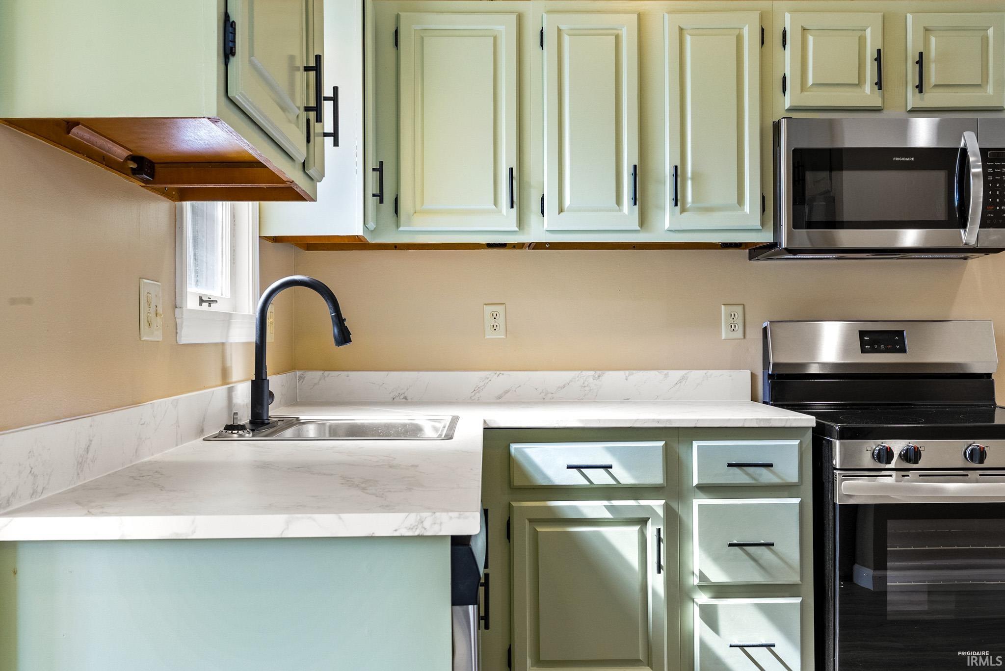 Kitchen featuring stainless steel appliances, light countertops, and green cabinets