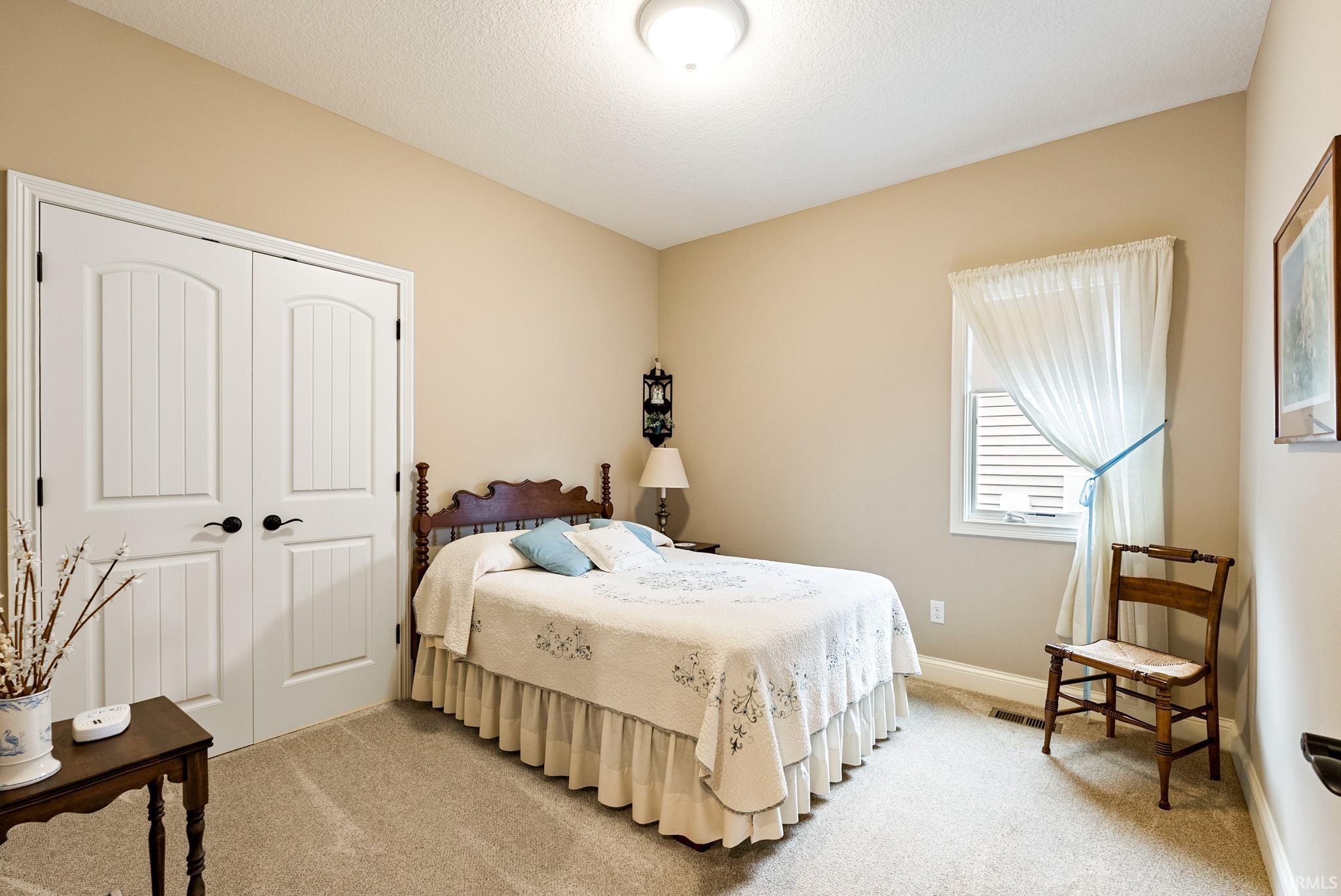 Bedroom with light carpet, a closet, and a textured ceiling